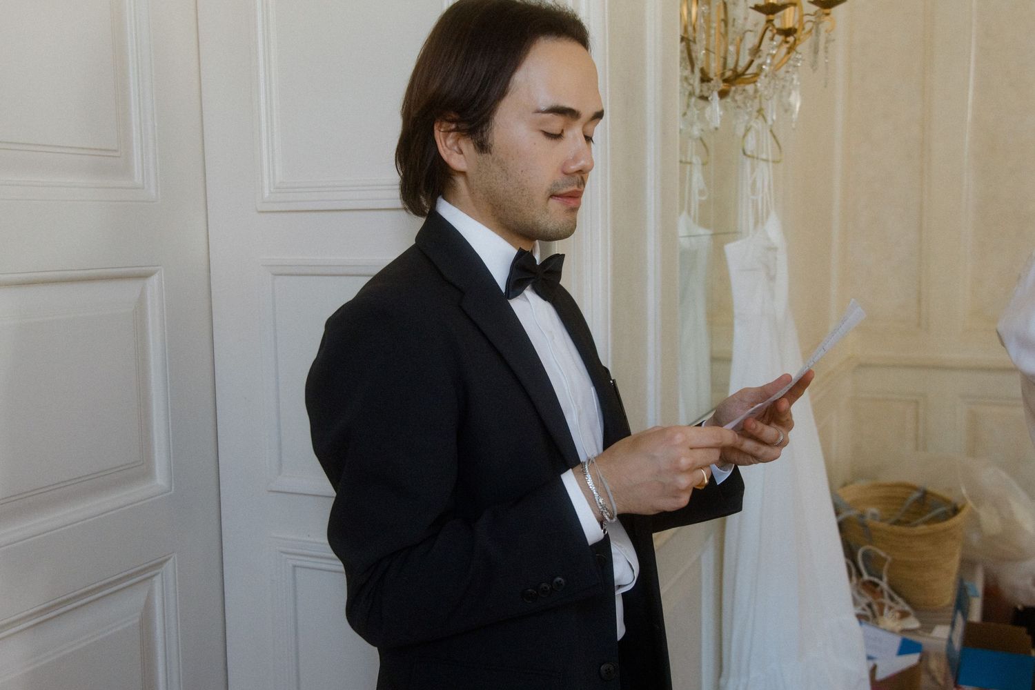 Formal preparation scene with black tuxedos in an elegant white room.