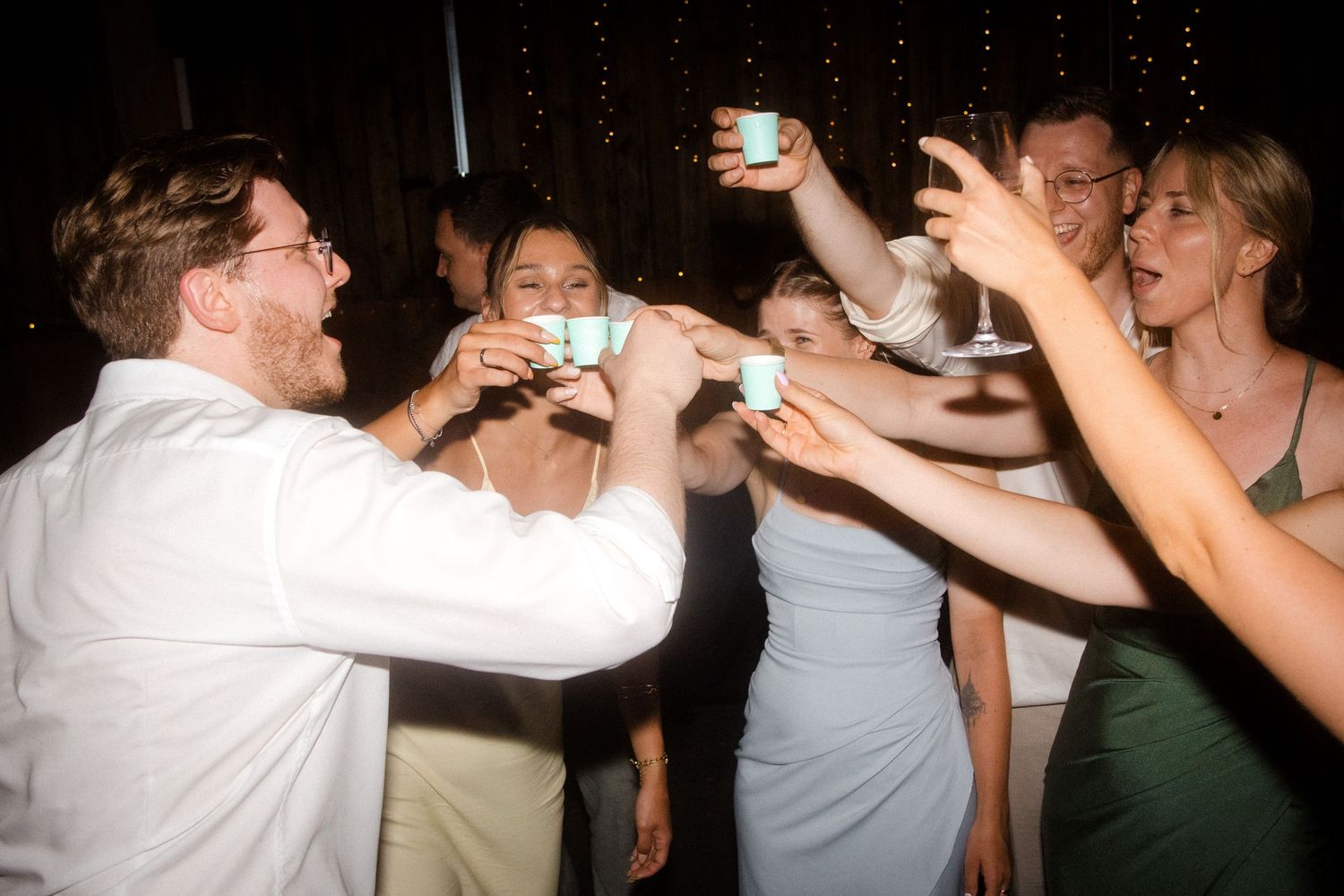 Guests dancing and celebrating under string lights at a nighttime reception.
