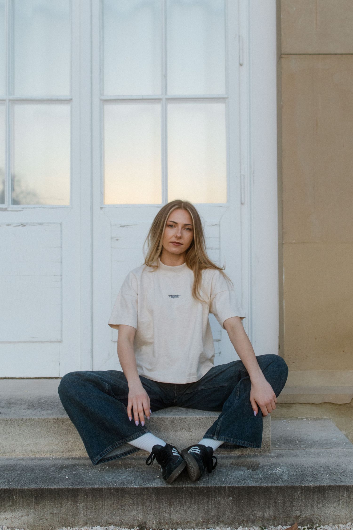 Person wearing casual attire sits on concrete steps in front of white doors in artistic triptych composition.
