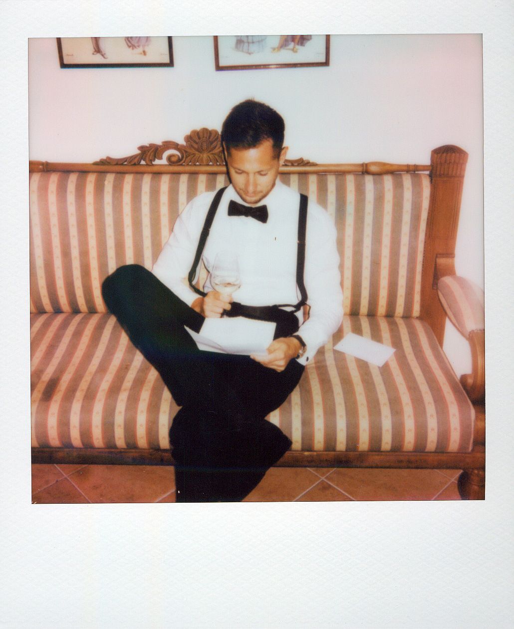 A person in formal attire sitting on a striped couch reading papers.