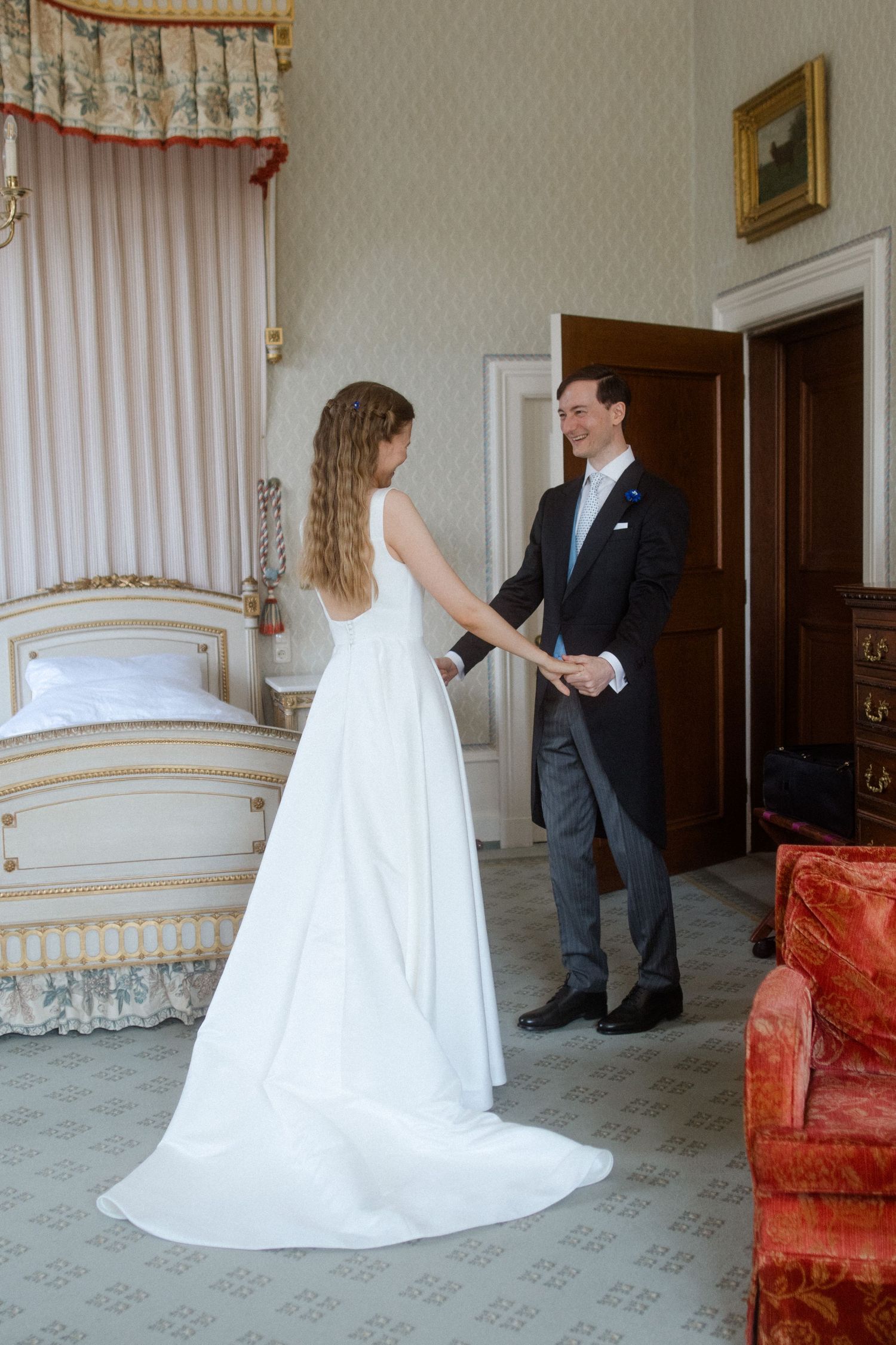 A couple shares a tender moment in an elegant room with vintage furniture and decor on their wedding day.