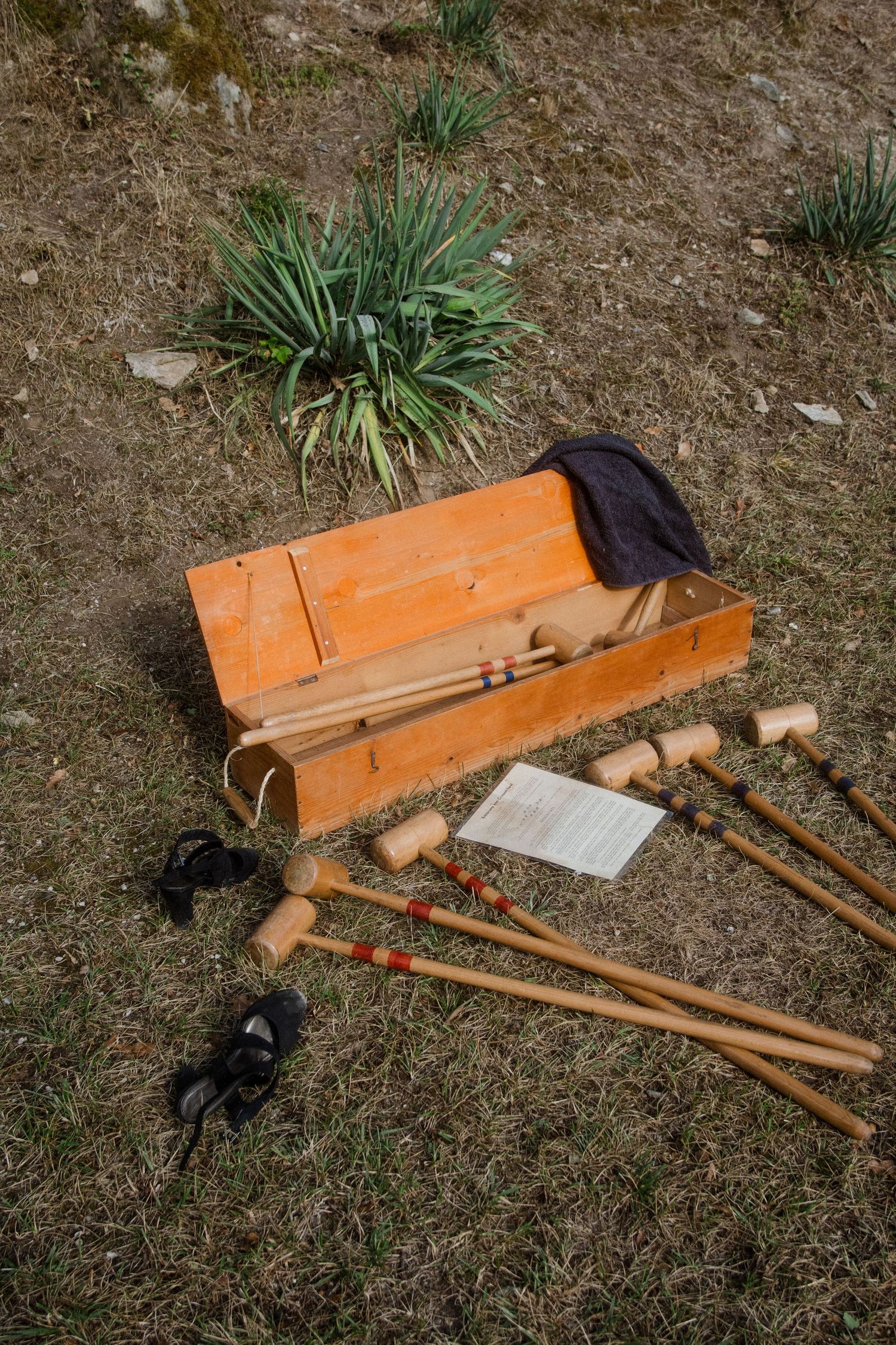 Wooden croquet mallets and equipment laid out on grass during a garden game setup.