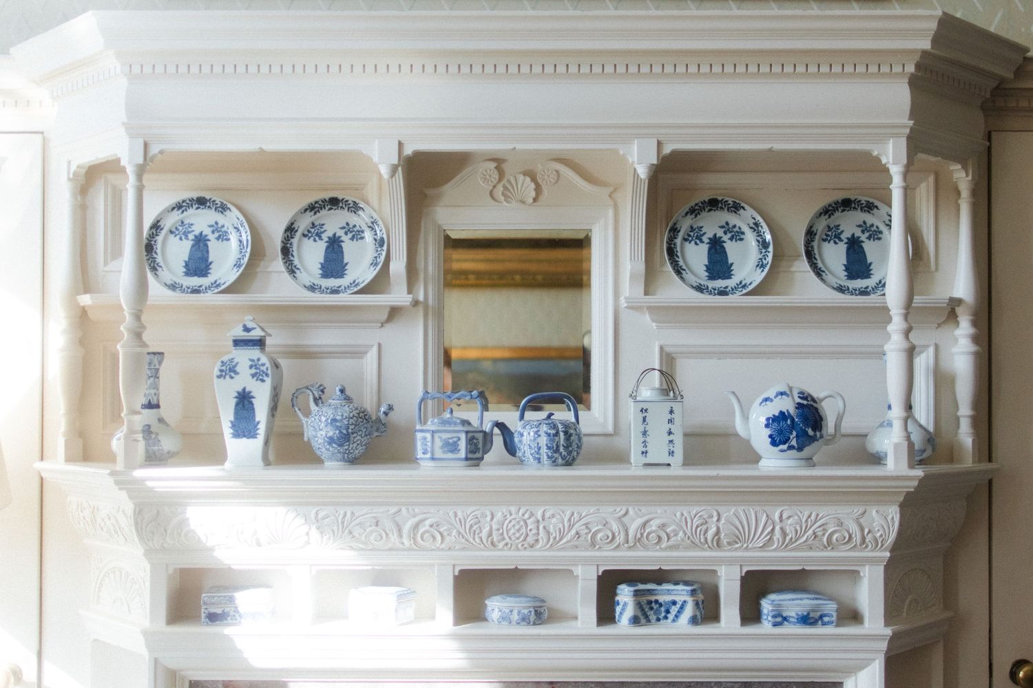 White shelving displaying collection of blue and white porcelain dishes and decorative plates.