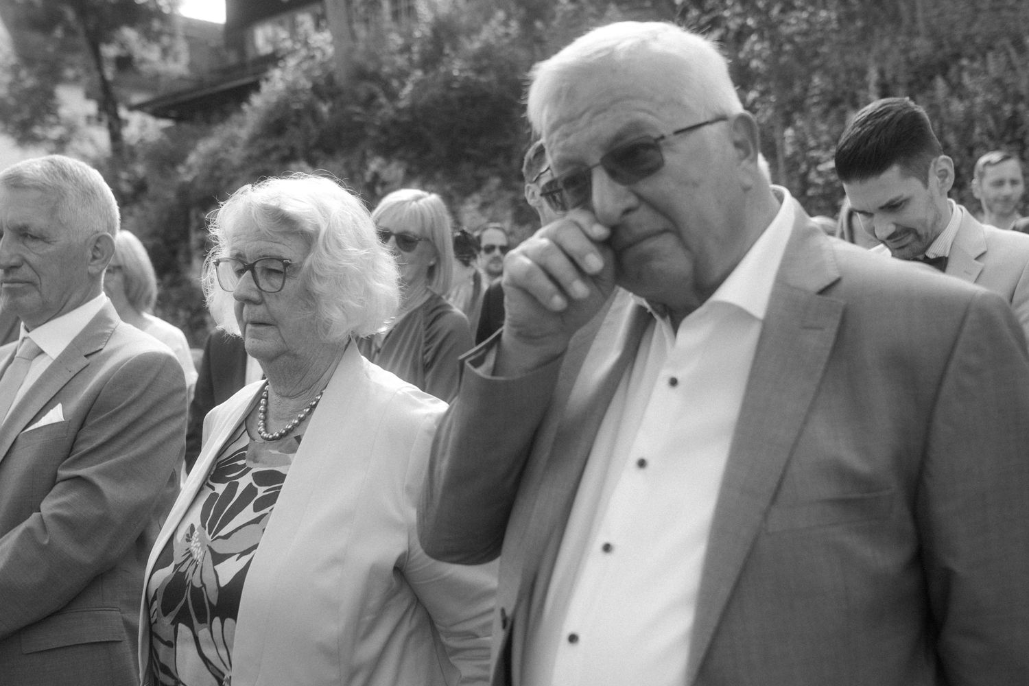 Black and white photo of wedding guests watching the ceremony with emotional expressions.