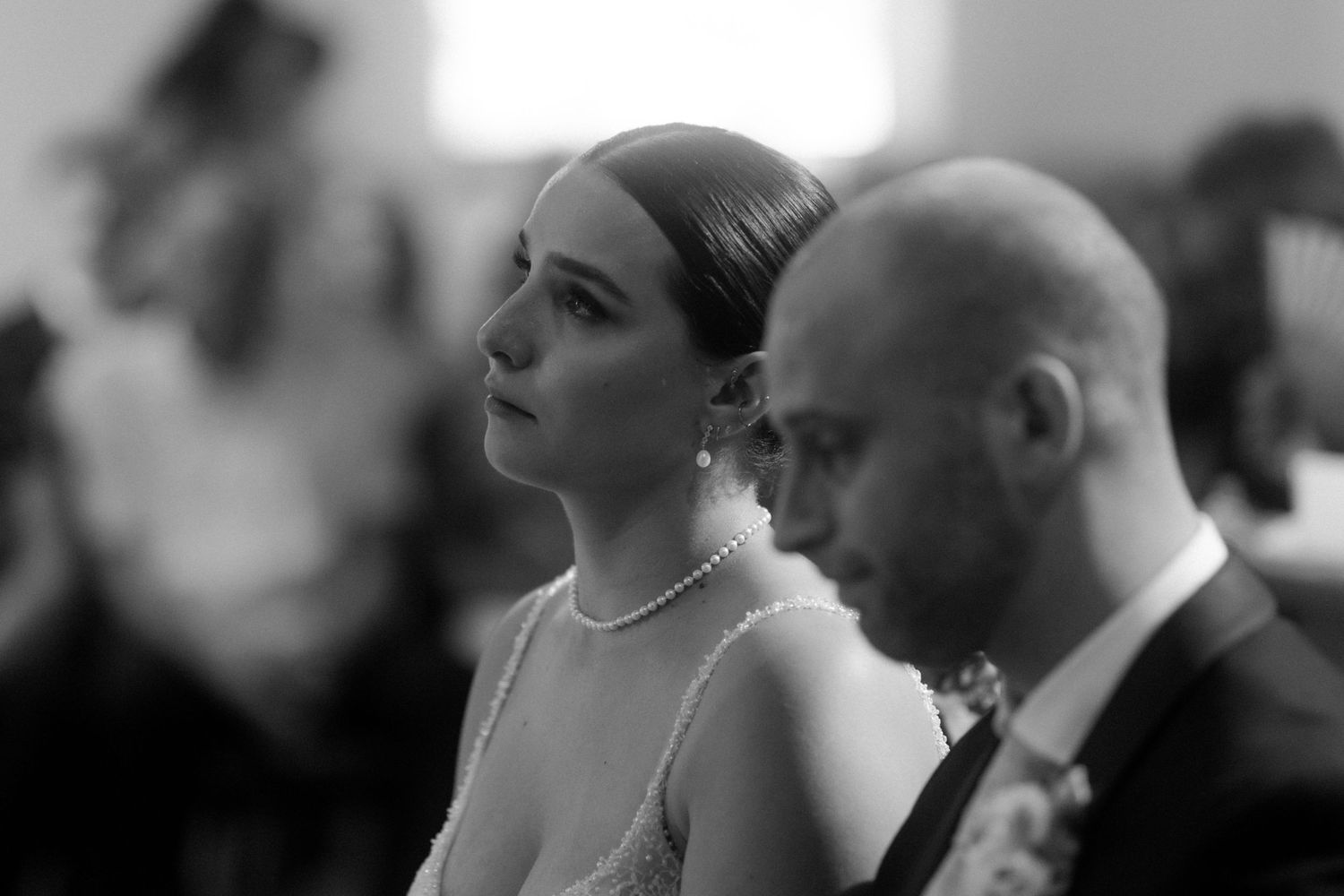 A black and white photo showing a solemn moment during a wedding ceremony in a church.