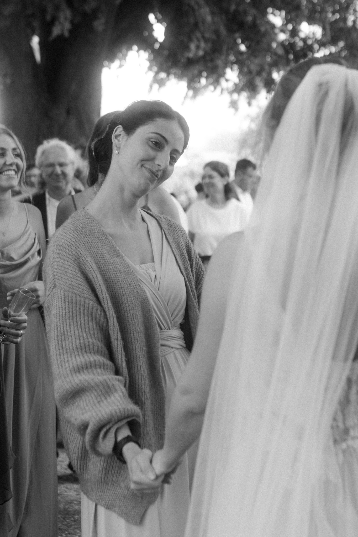 Black and white photo of guests greeting bride during outdoor wedding reception.