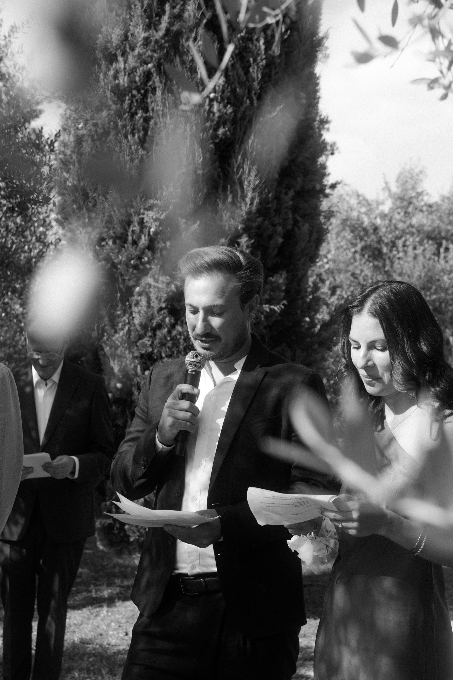 Black and white photo of wedding guests enjoying speeches in an Italian garden.
