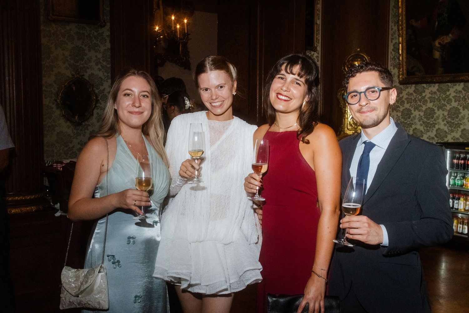 Group of friends celebrating with drinks at an elegant evening event.