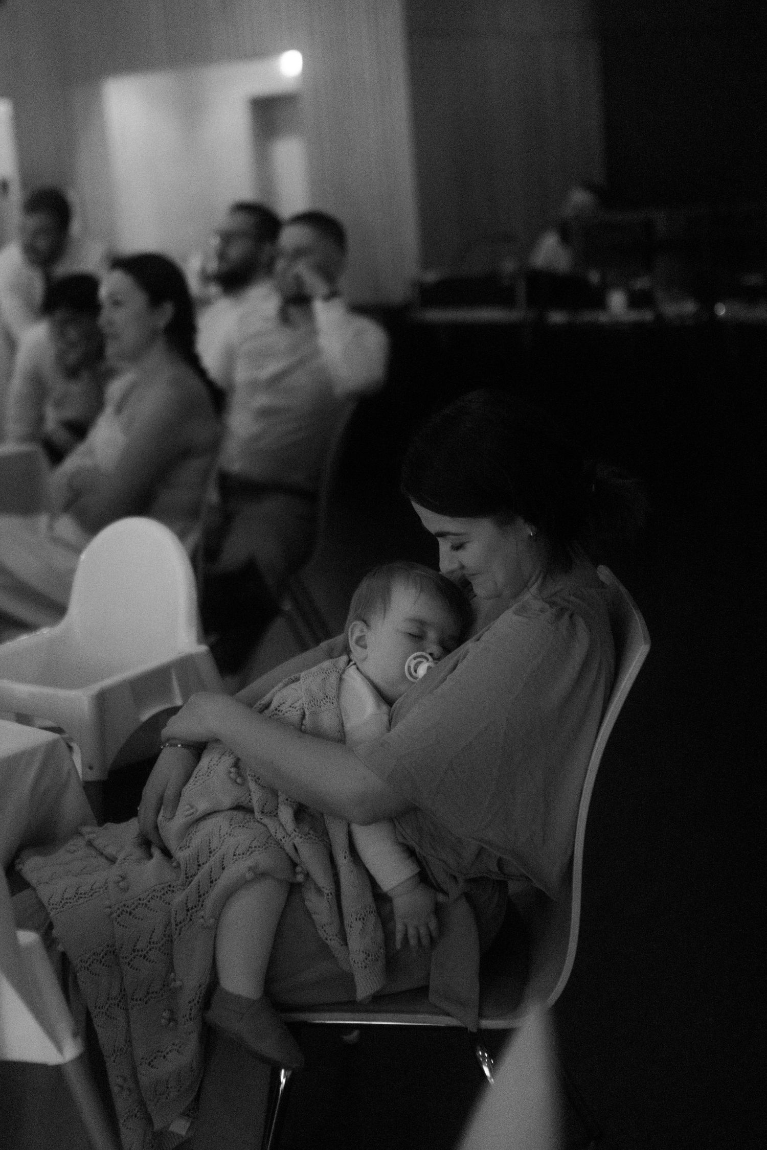 A tender black and white photo of a baby being cradled during an event.