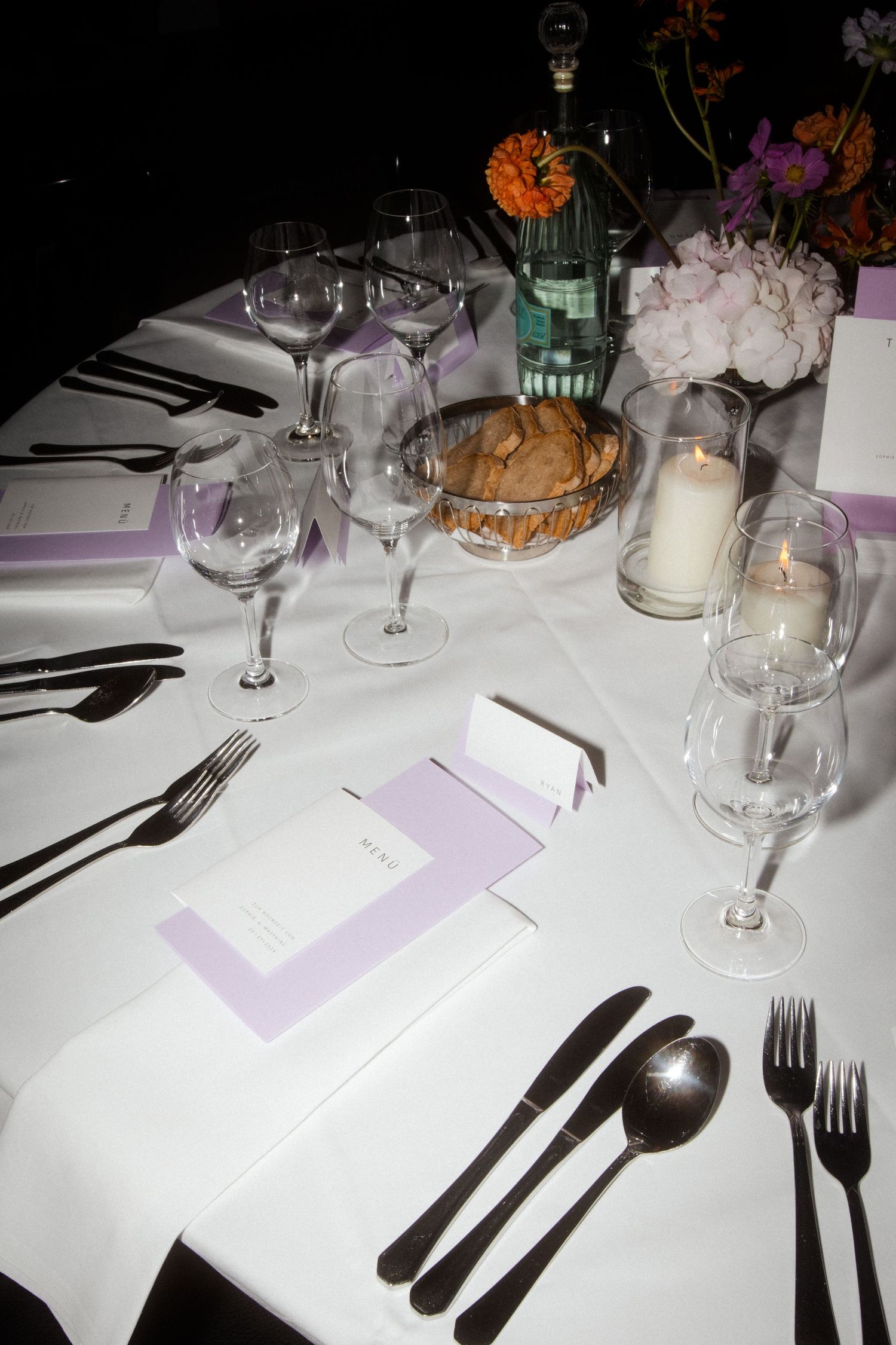Formal place setting at an elegant dinner table with wine glasses and candles.