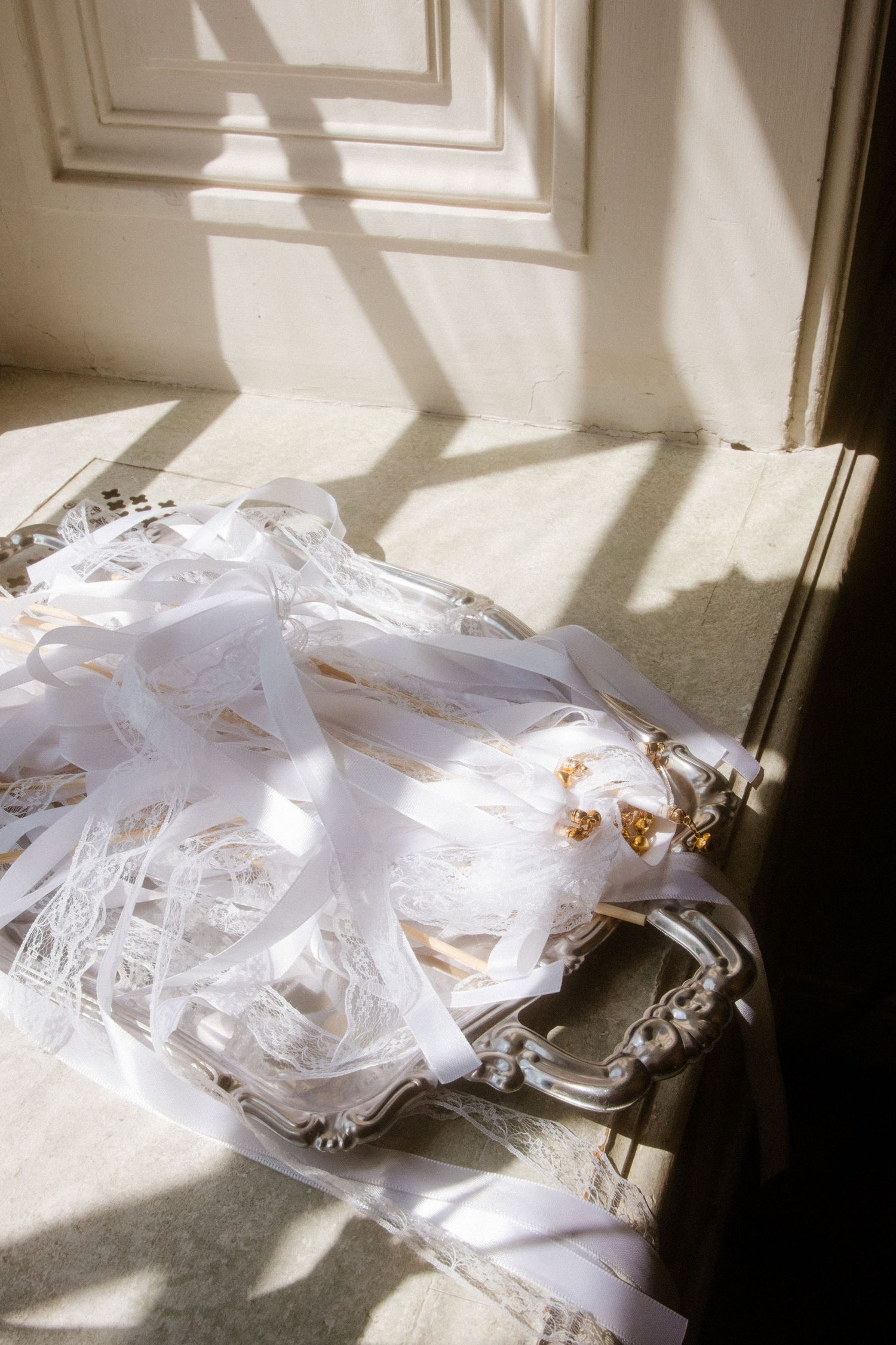 White delicate fabrics and textiles laid out in soft sunlight streaming through a window.