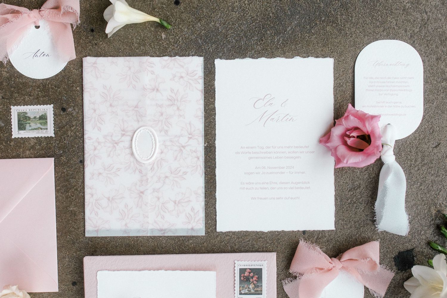 Wedding stationery suite in pink and white tones arranged in flat lay composition.