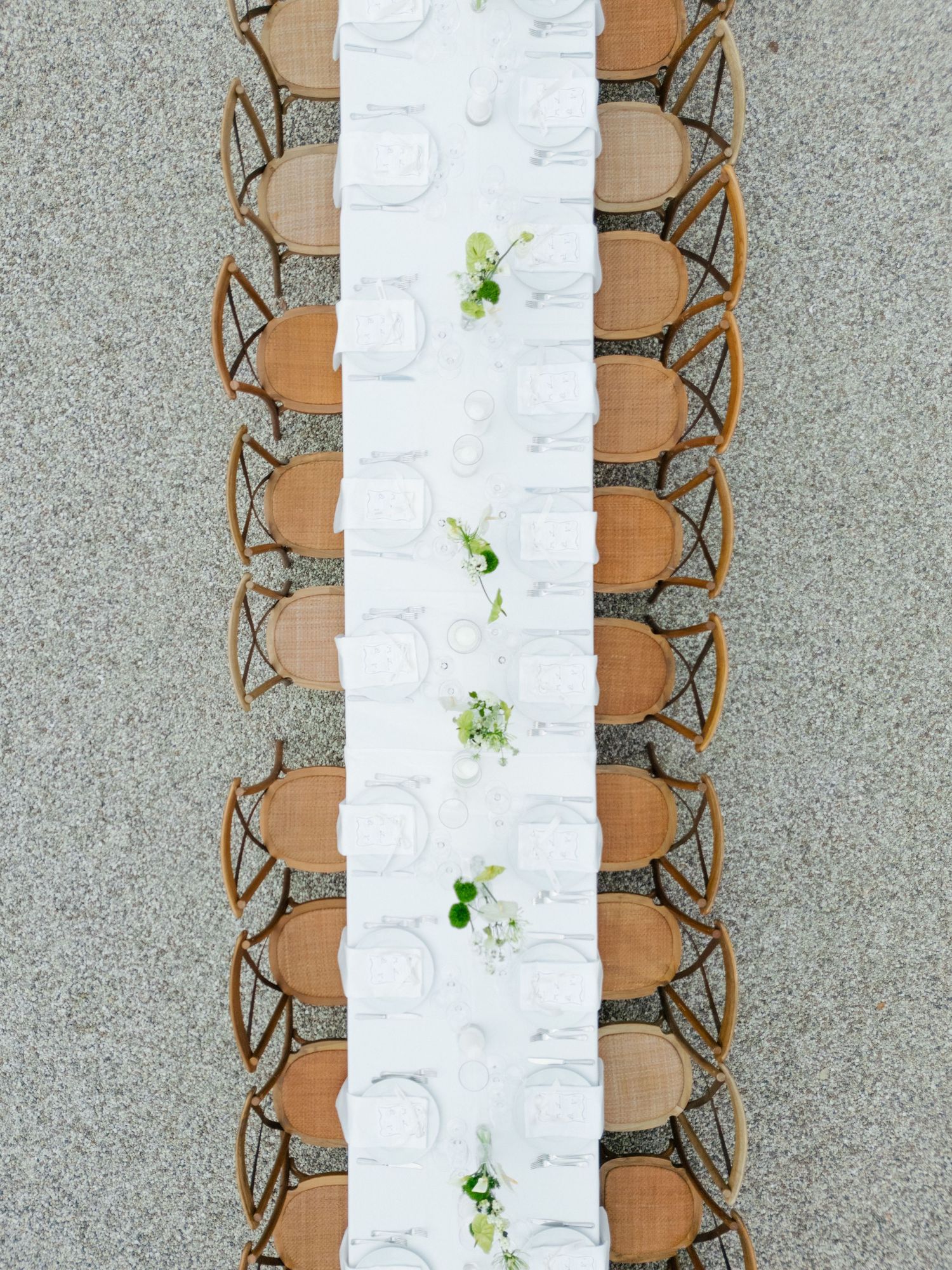 Modern place setting with crisp white tablecloth, brown napkins and elegant butterfly table numbers displayed in a row.