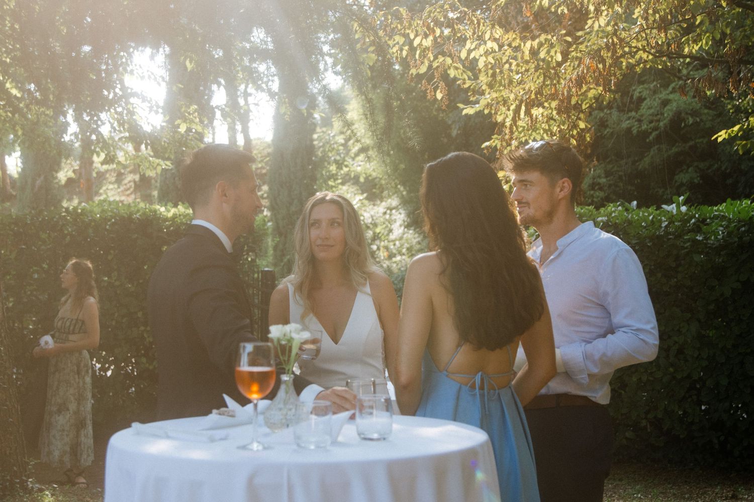 Guests enjoying drinks at outdoor reception during golden hour.