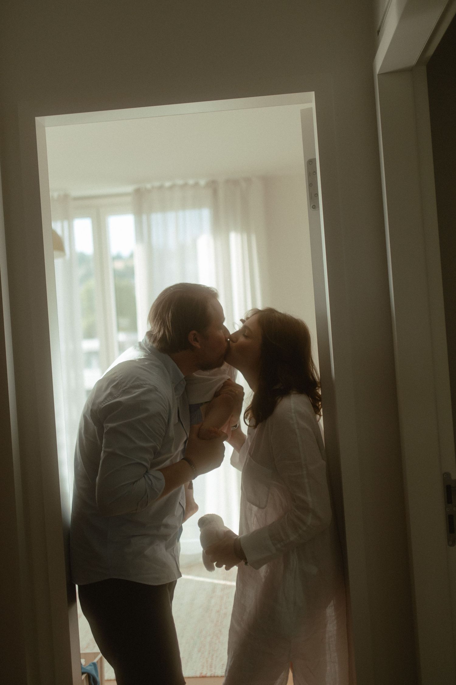 Silhouettes of people embracing in a sunlit hallway create a romantic and atmospheric scene.