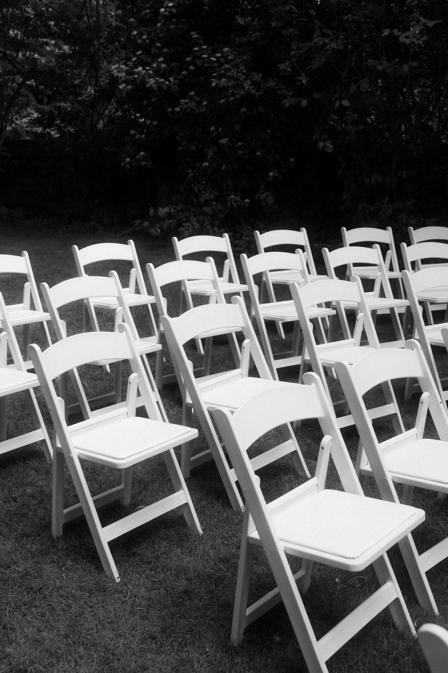 Rows of white folding chairs set up on grass for an outdoor wedding ceremony.
