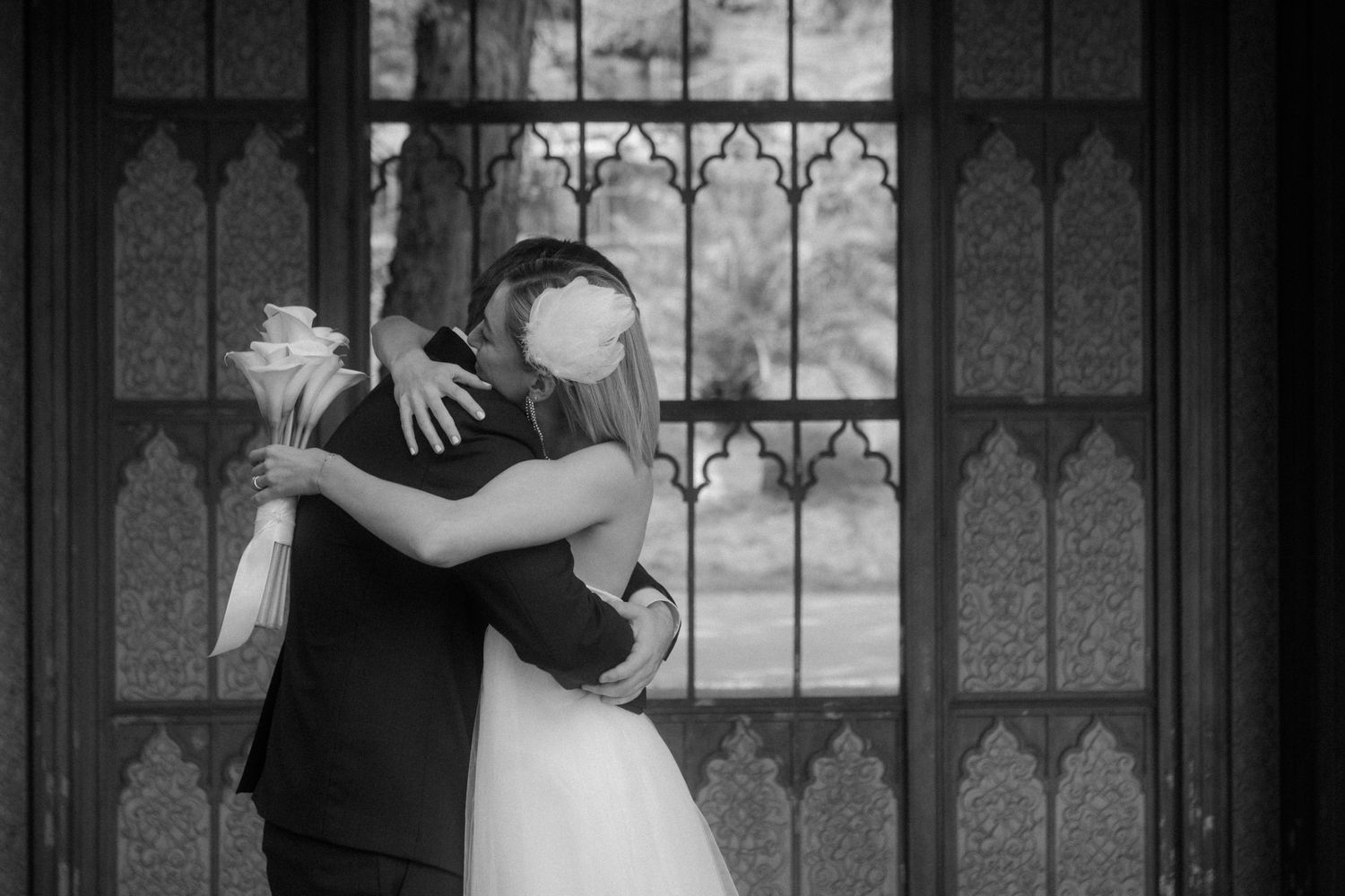 Tender moment between bride and groom embracing in black and white photography.