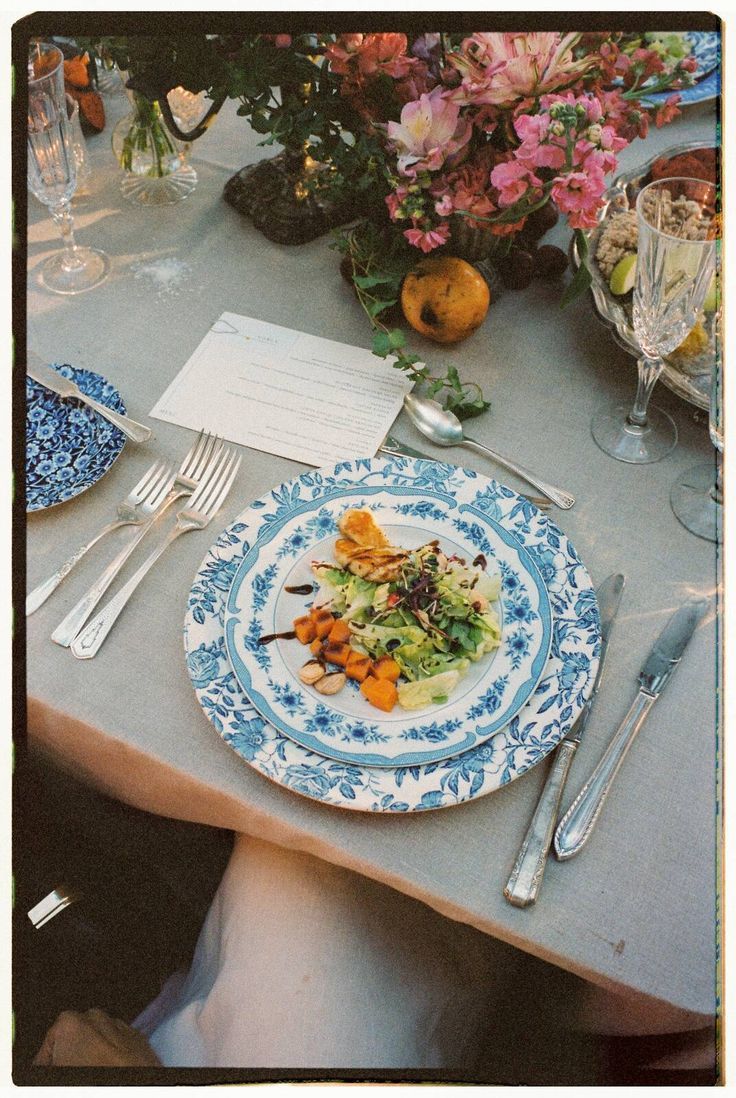 Elegant place setting featuring blue and white china plate with colorful food presentation.
