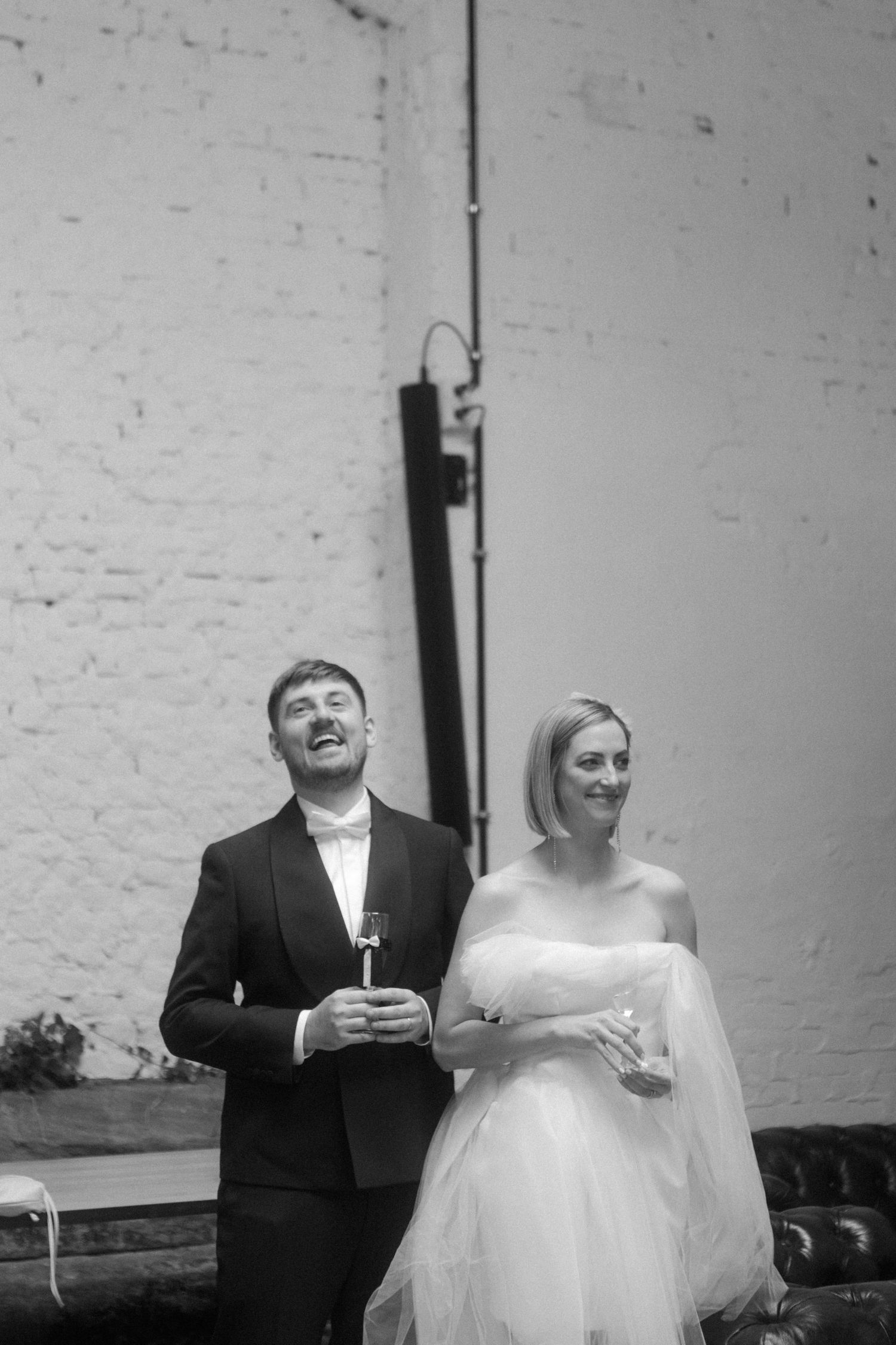 A couple looks up and laughs during a candid moment at their wedding reception.