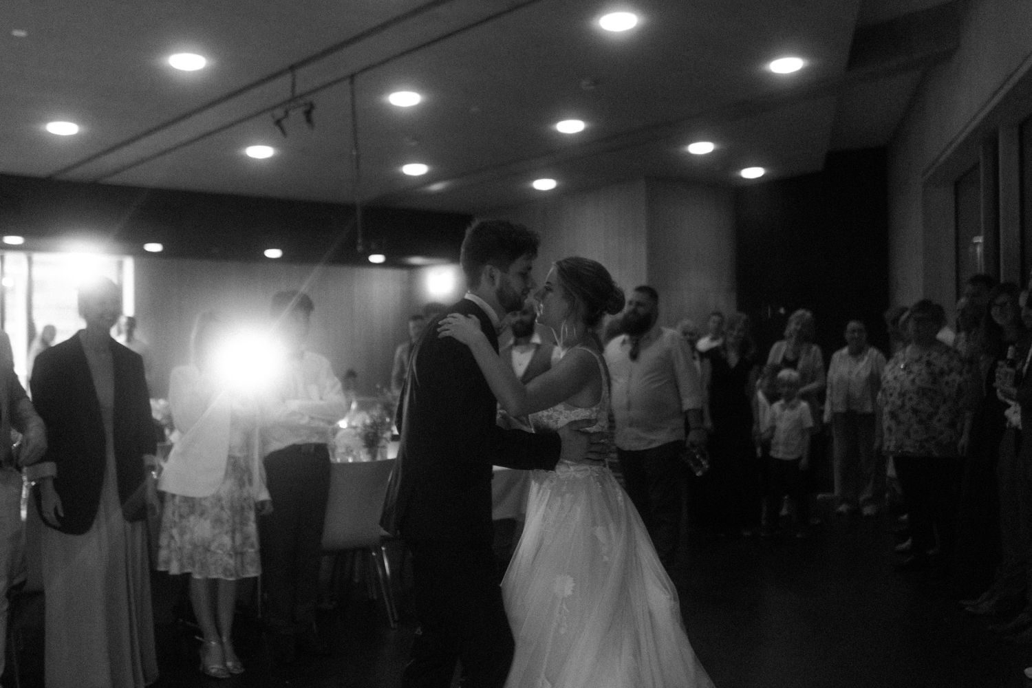 A black and white photo captures a tender first dance moment at a wedding reception.