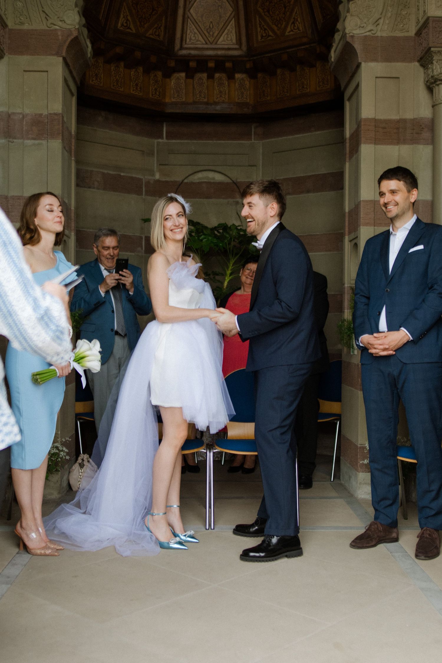 Modern wedding ceremony in architectural space with bride in short dress and mint shoes.
