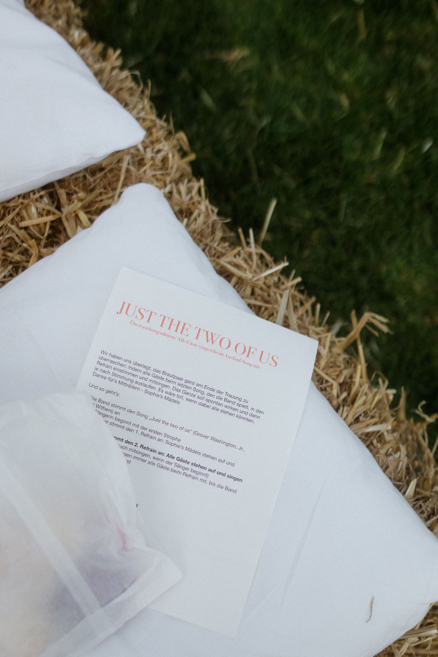 Wedding program titled 'Just the Two of Us' resting on hay bales.