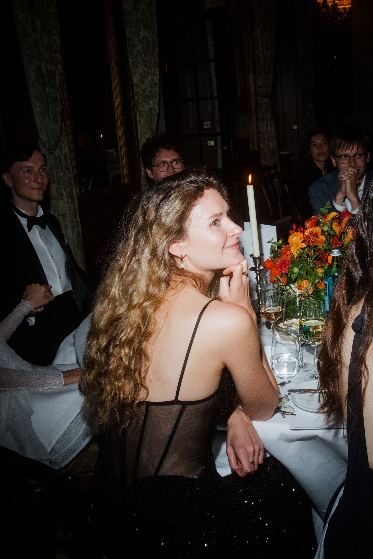 Guests celebrating at an elegant evening wedding reception with floral centerpieces.
