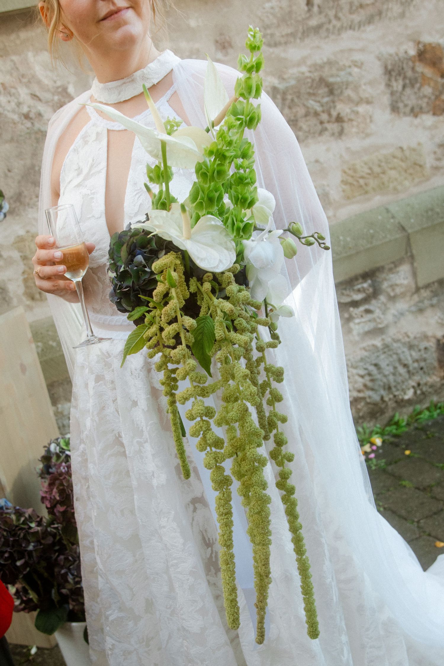 Close-up of white lace wedding dress with cascading green floral details.