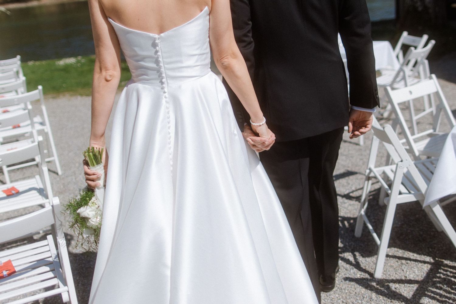 Bride and groom walking hand in hand down the aisle at an outdoor wedding ceremony.