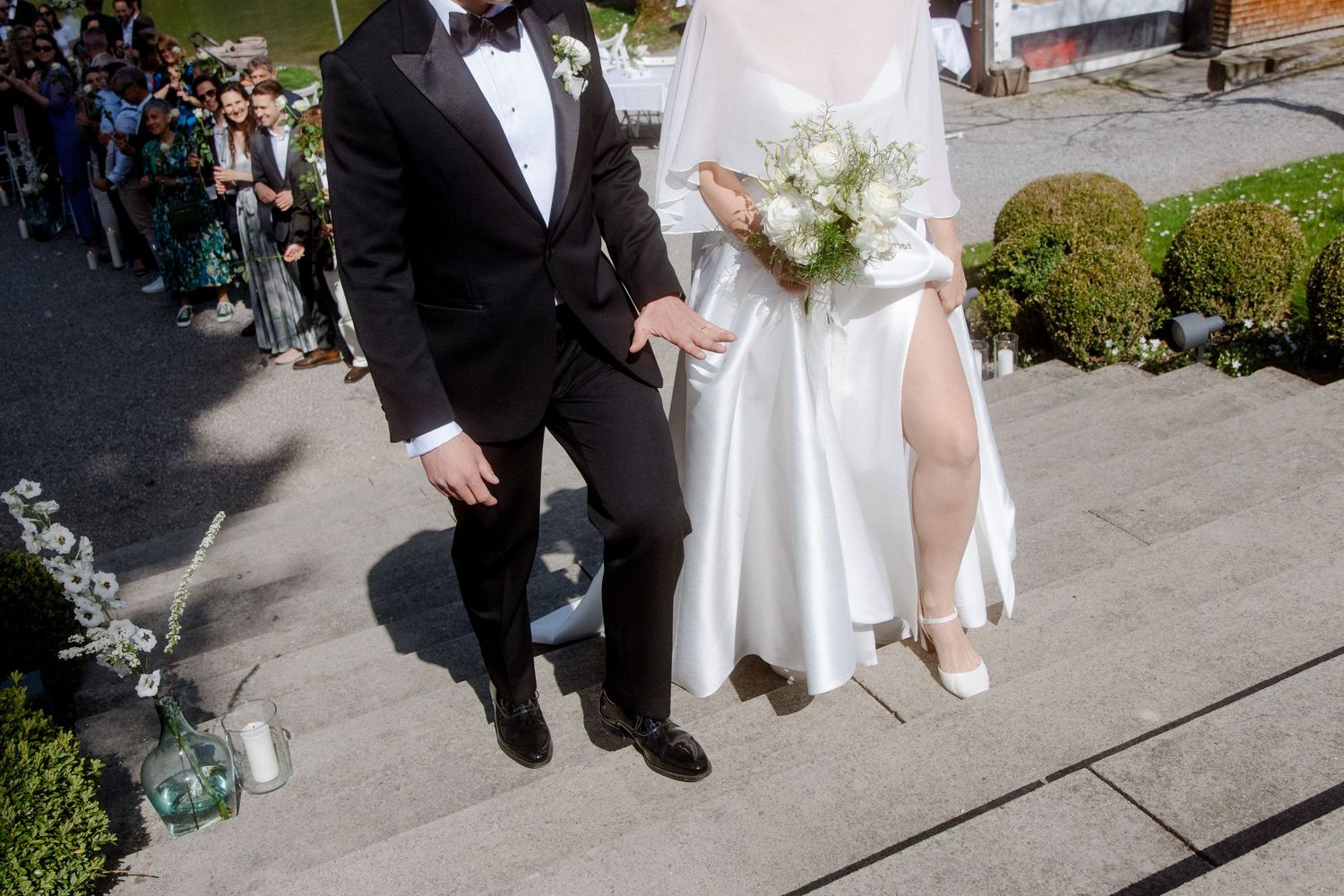 Bride and groom in elegant wedding attire descending stone steps together on their wedding day.