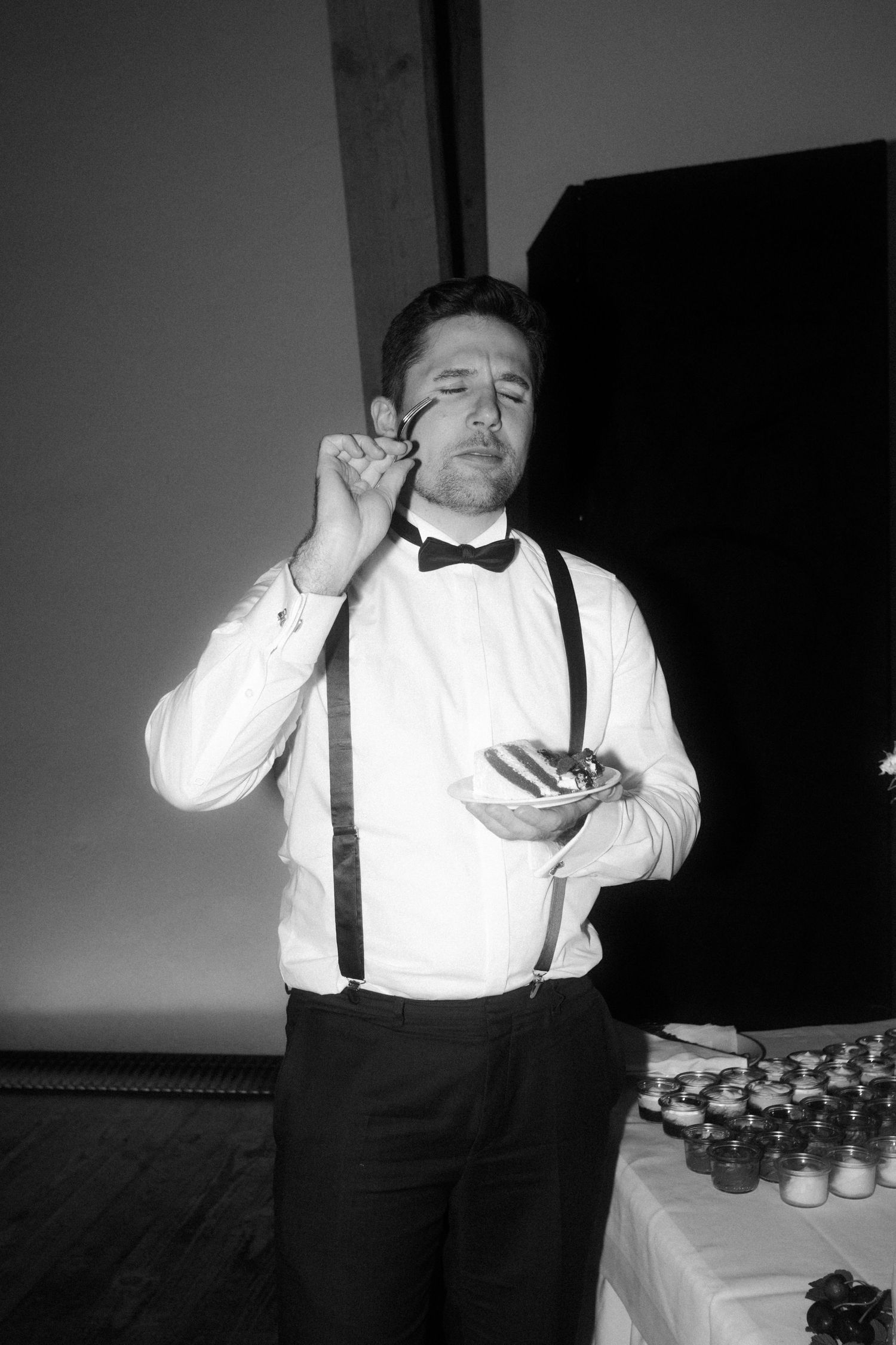 Person in formal attire with suspenders and bowtie at event.