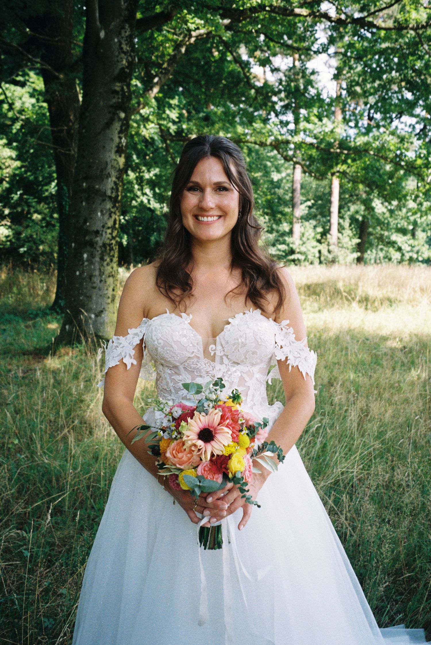 A beautiful bridal portrait series showing a white lace wedding dress and colorful summer bouquet in a natural outdoor setting.