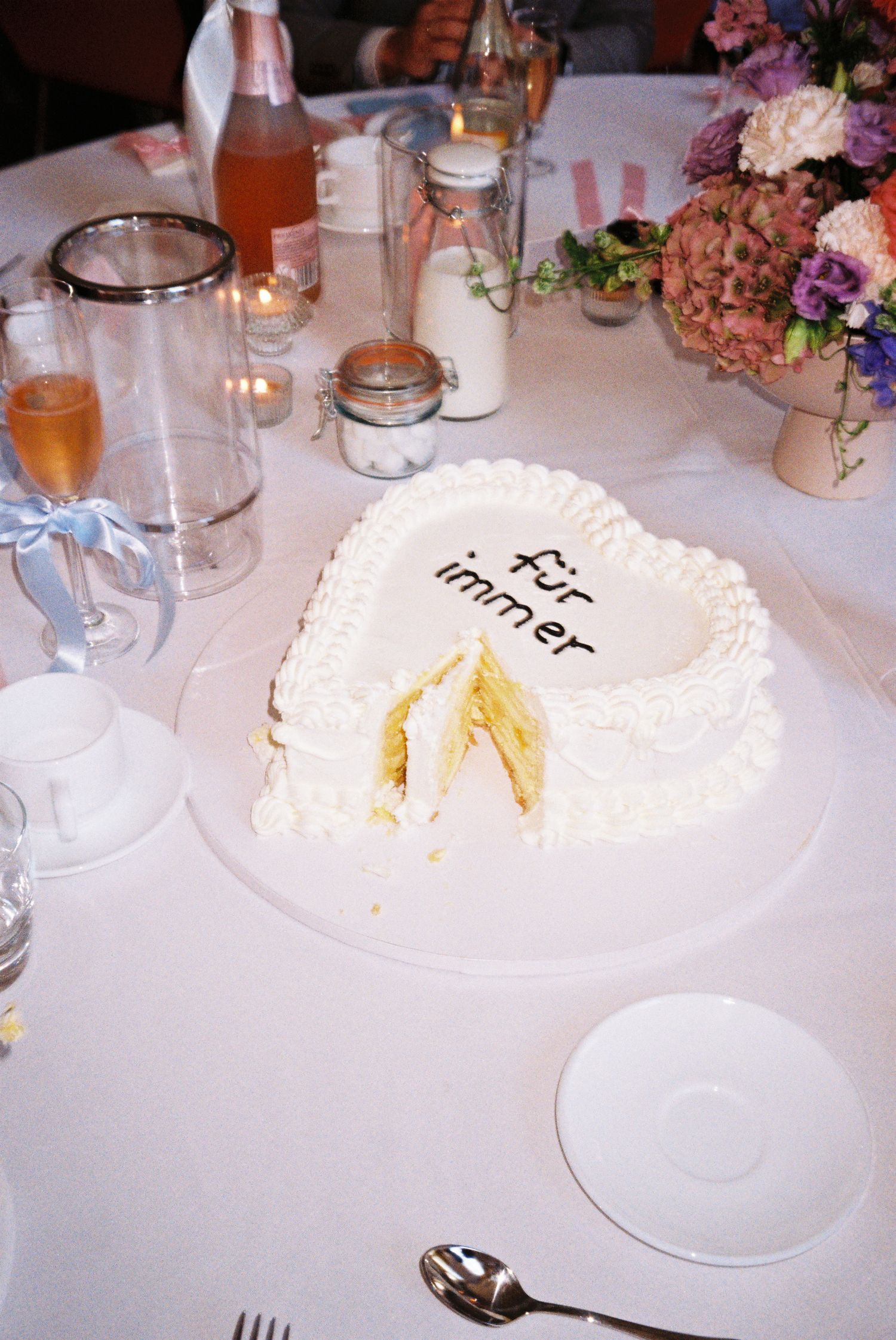 Elegant white cake stands and table settings with delicate floral arrangements create a romantic wedding reception atmosphere.