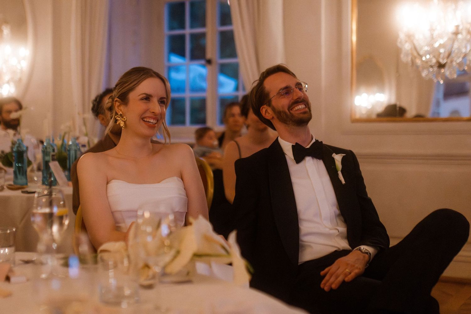 Candid moments of laughter and joy during an elegant ballroom wedding reception.