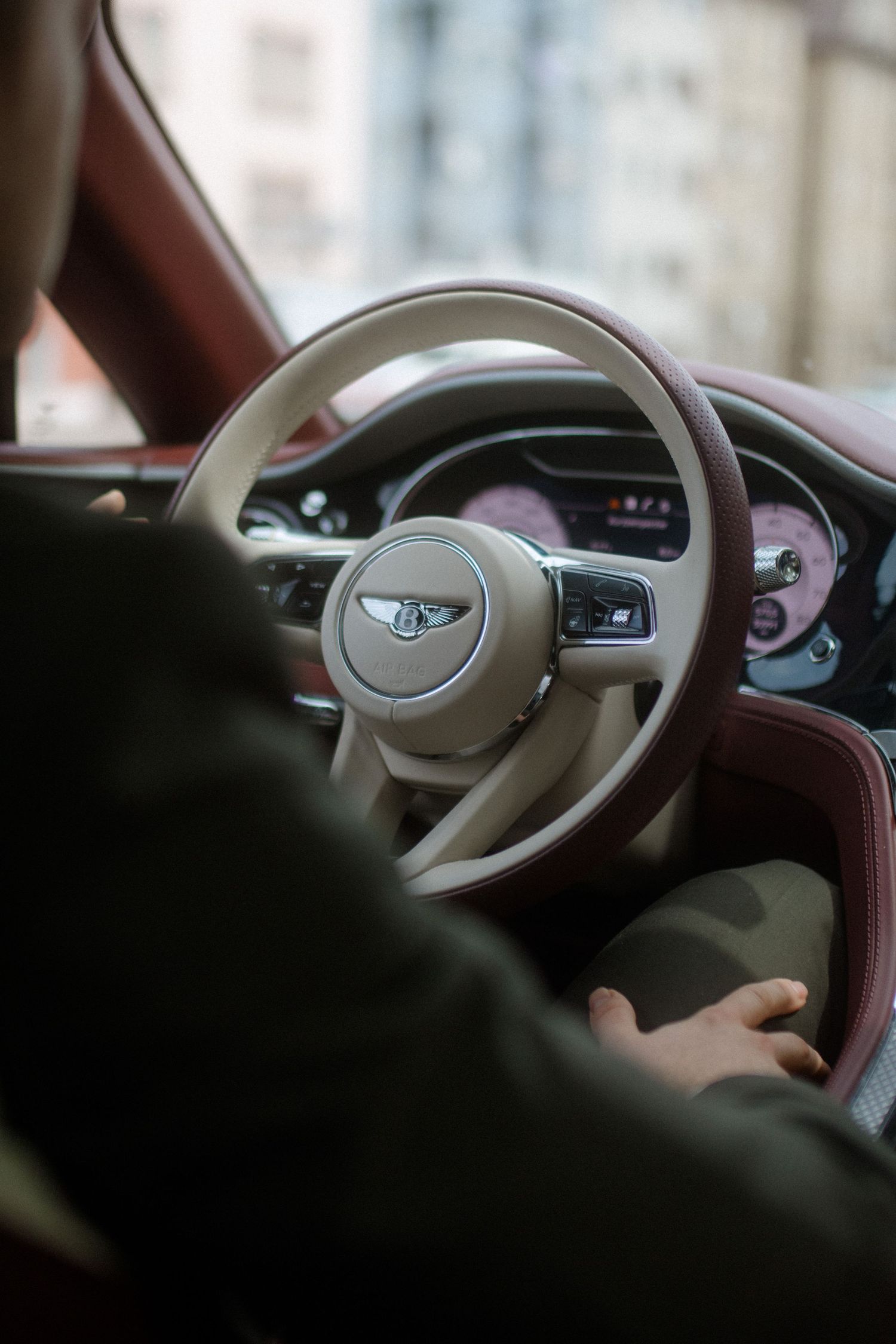 Interior view of a Bentley luxury car showing the steering wheel and dashboard.