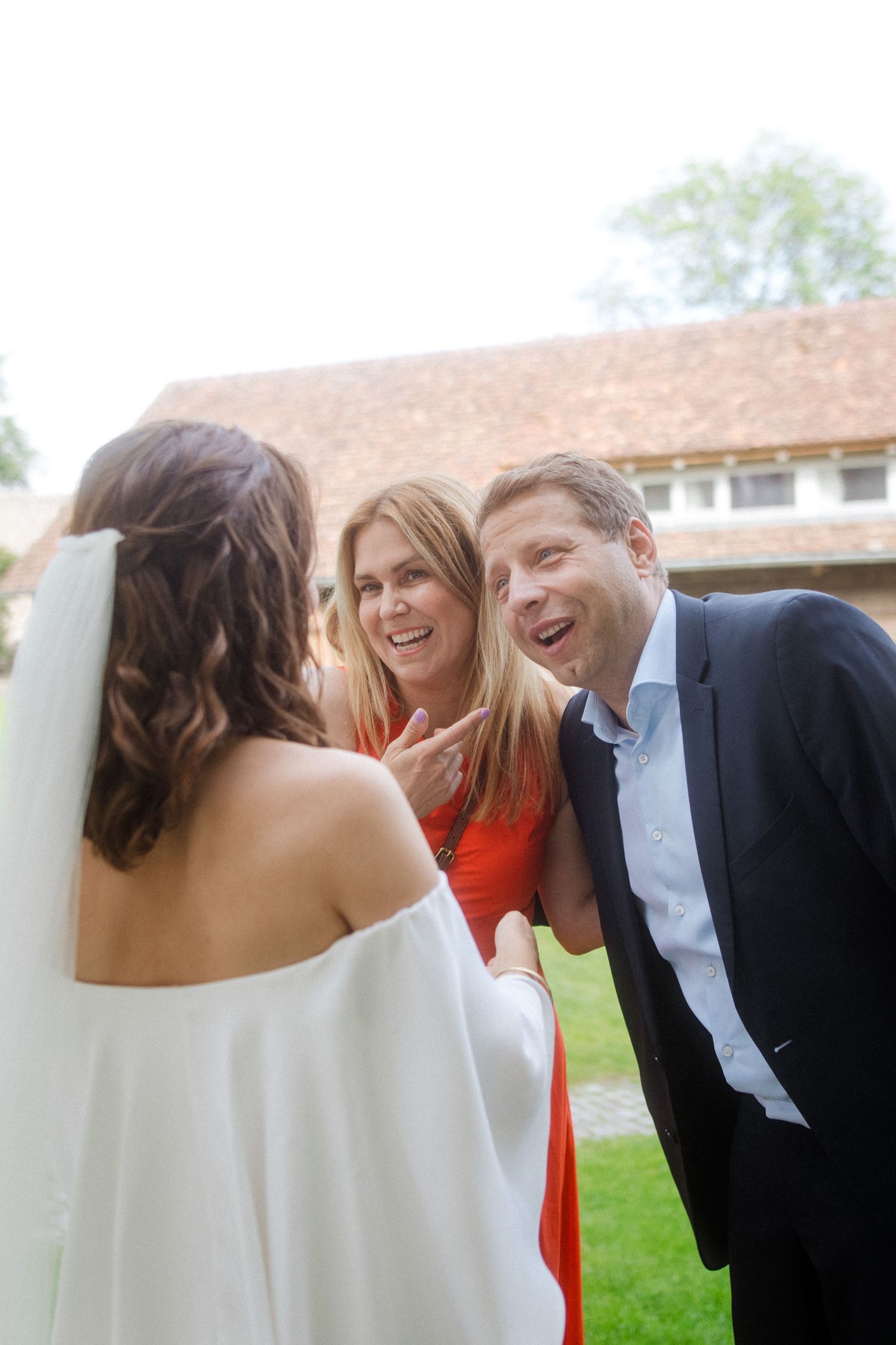 Joyful wedding celebration moment shared between guests on sunny outdoor lawn.
