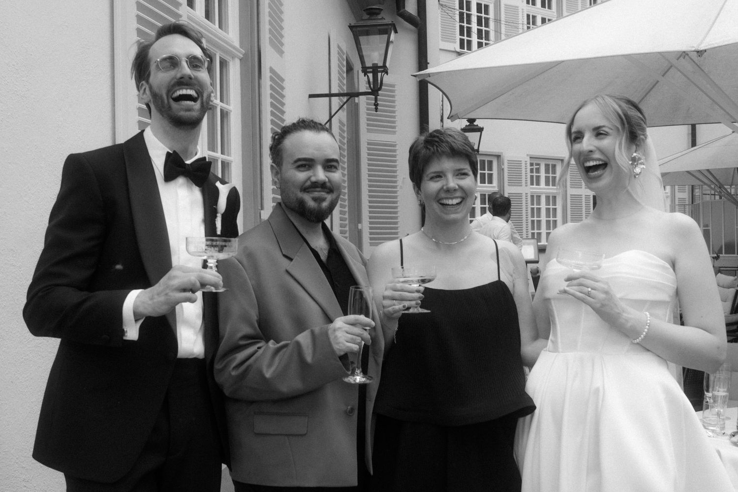 Wedding guests sharing drinks and laughter during an outdoor celebration.
