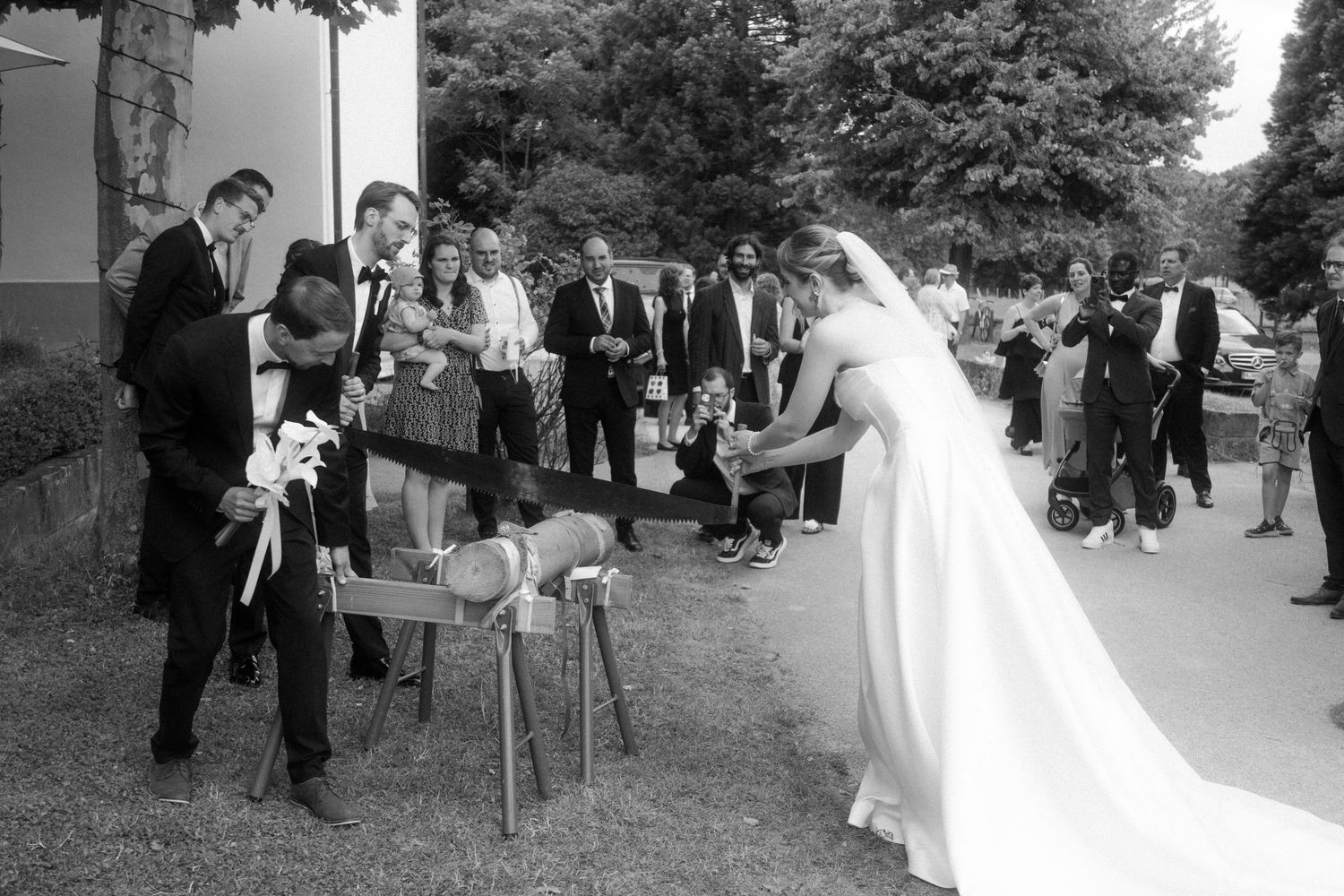Black and white photo of wedding guests gathered outdoors for a celebration.