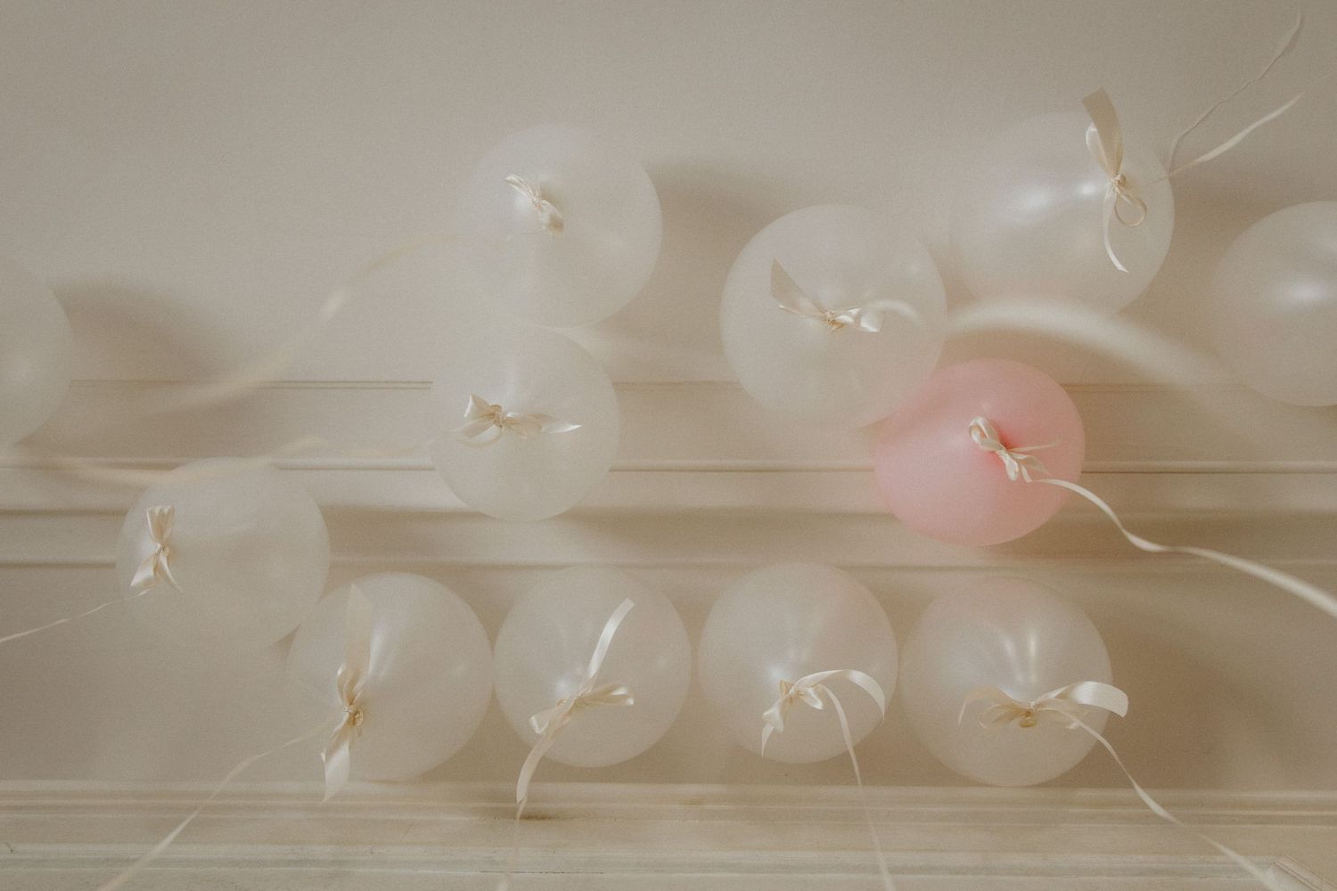 Soft focus image of delicate white and pink balloons creating a dreamy atmosphere.