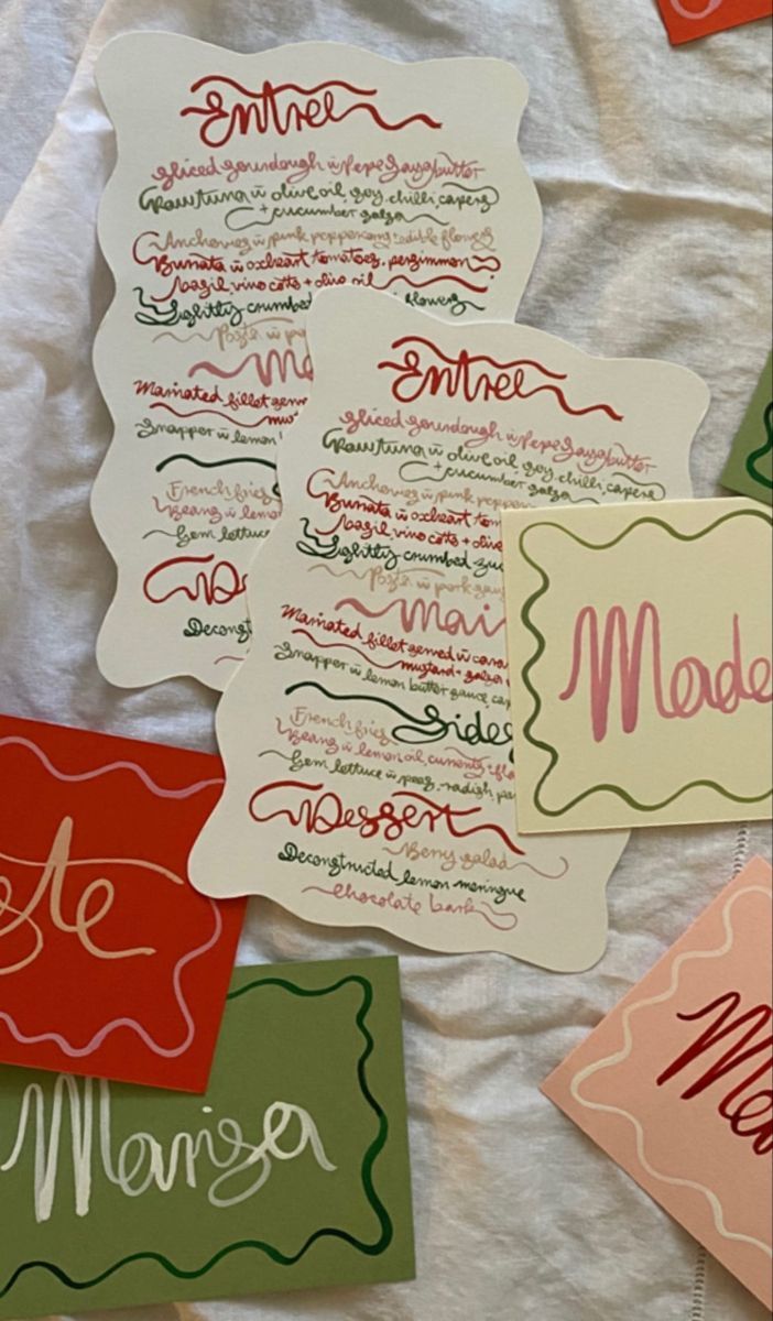 Decorative wedding menu cards with red and green calligraphy on scalloped paper.