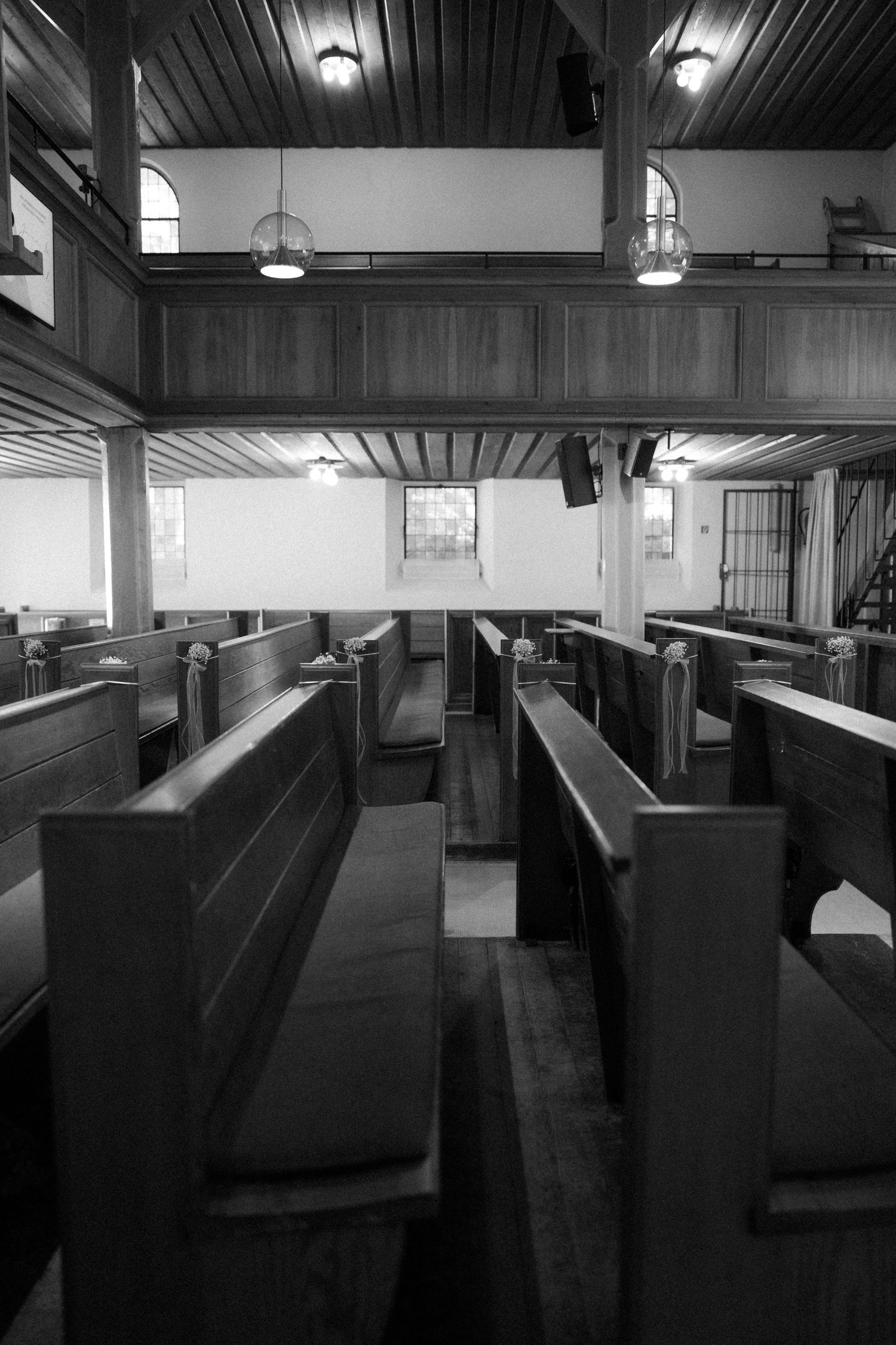 Black and white interior of church with wooden pews and vaulted ceiling.