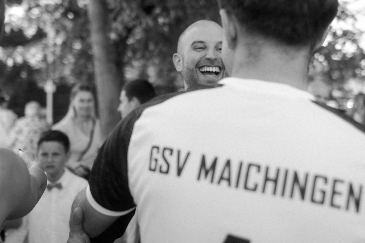 A black and white photo showing a supporter wearing a GSV Maichingen jersey at an outdoor gathering.