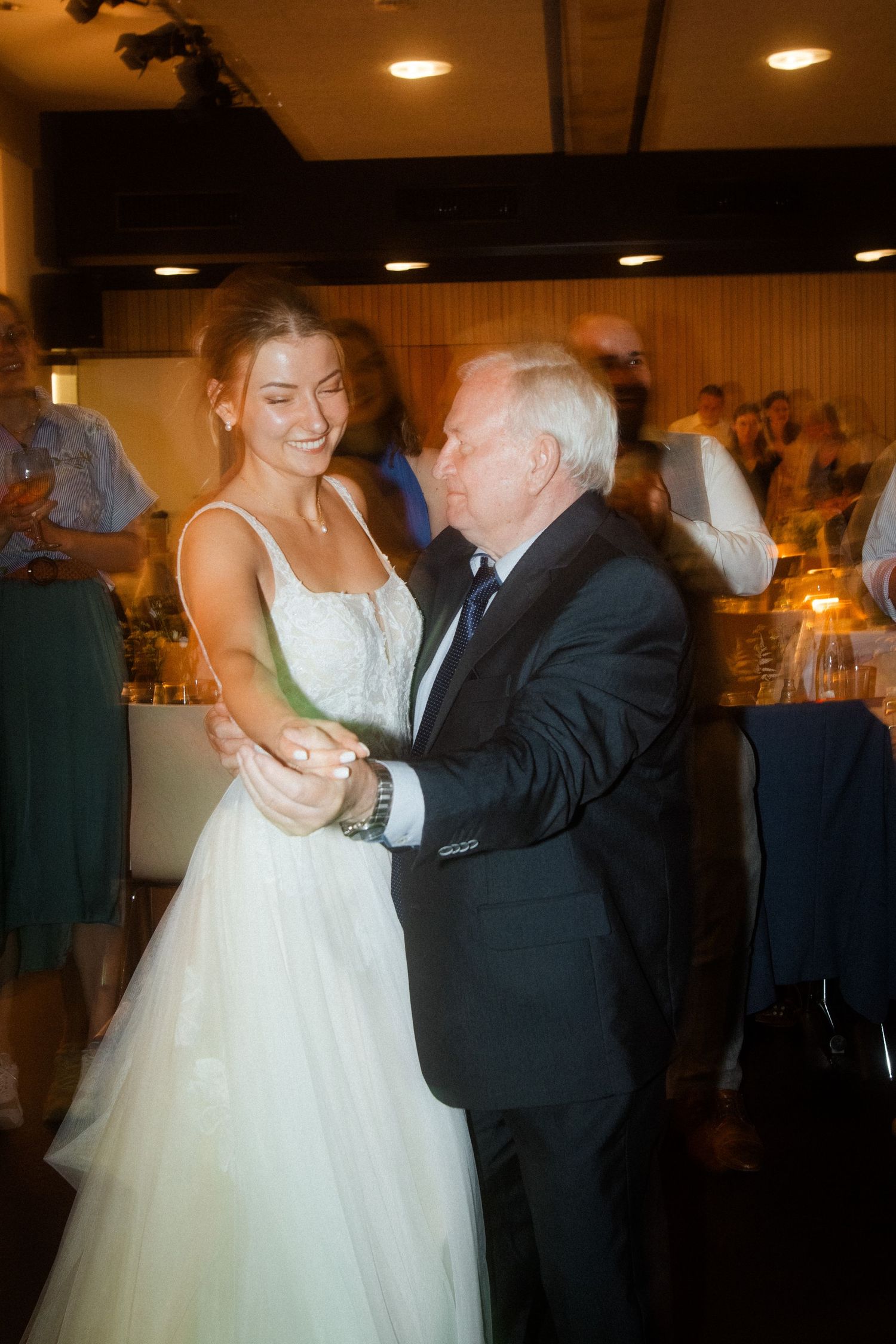 Sweet moment captured of bride dancing with elderly guest at wedding reception.