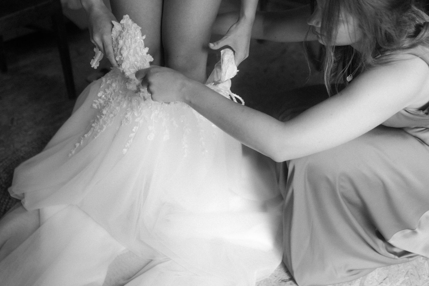 Close-up details of a white wedding dress being adjusted.