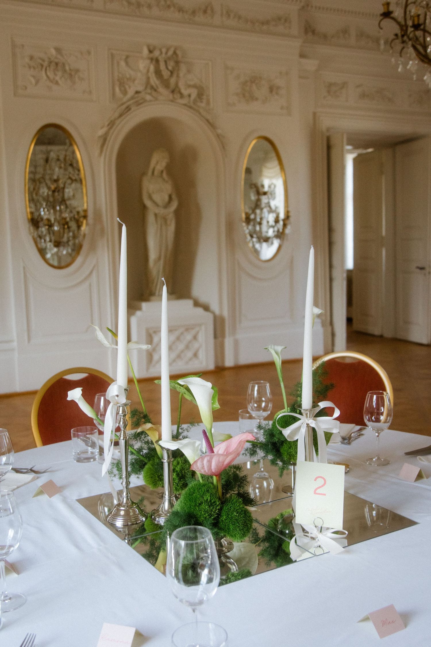 Luxurious wedding reception hall with ornate white walls and elegant table settings.