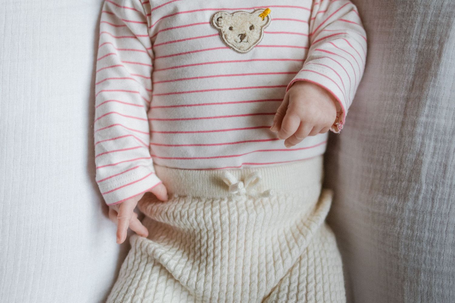 Baby wearing a striped pink and white outfit with a bear design.