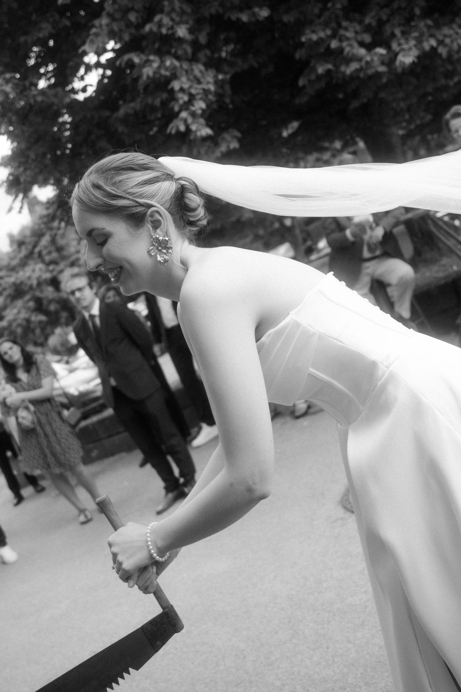 Wedding party participates in traditional German log cutting ceremony outdoors.
