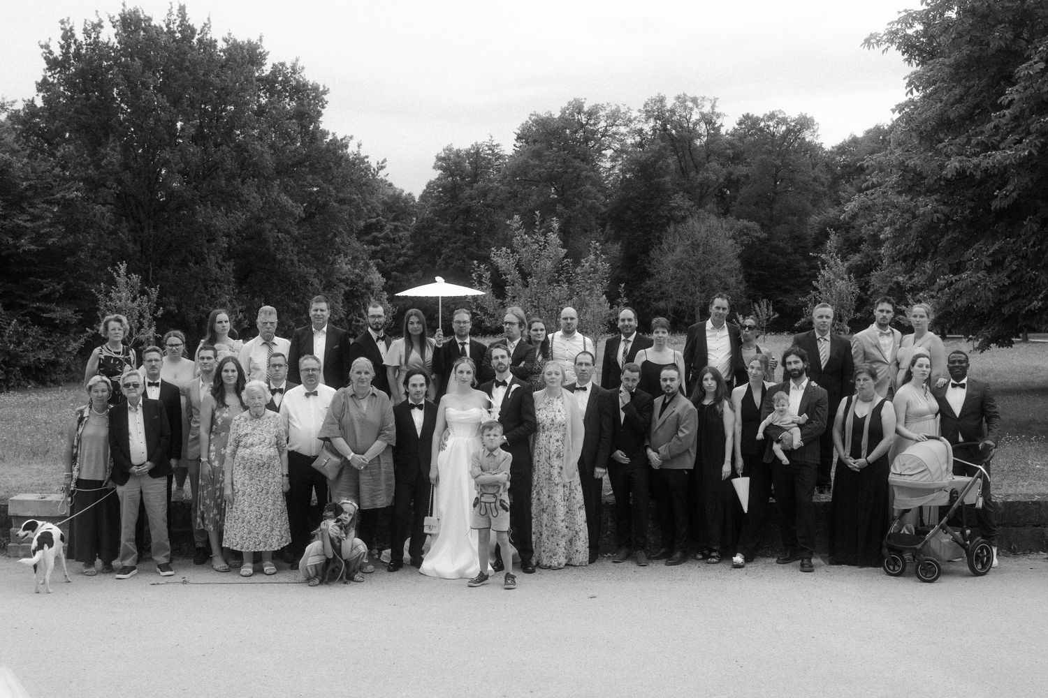 Large wedding party poses together in black and white for a formal group portrait.