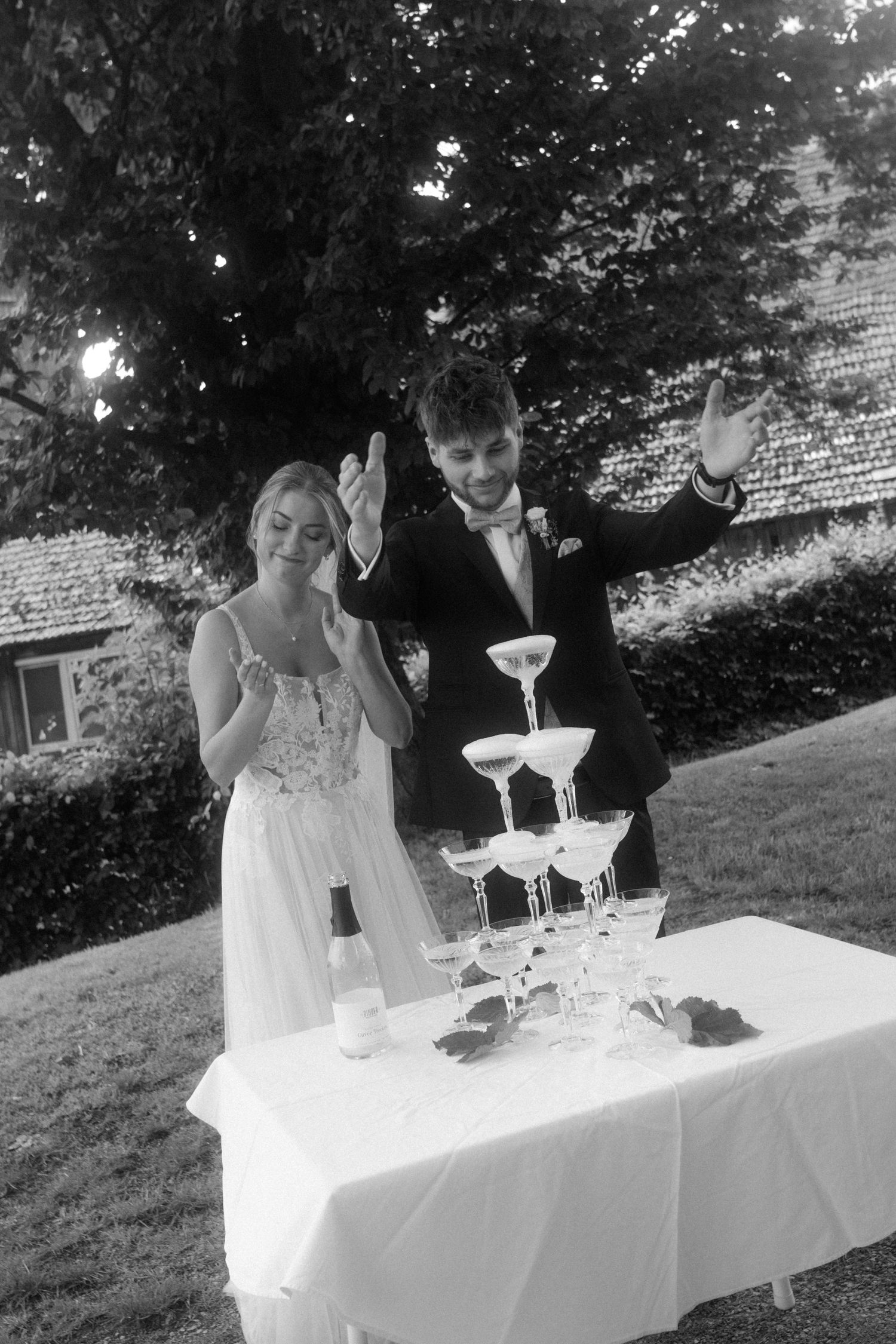 Wedding celebration with champagne tower and guests showing excitement outdoors.