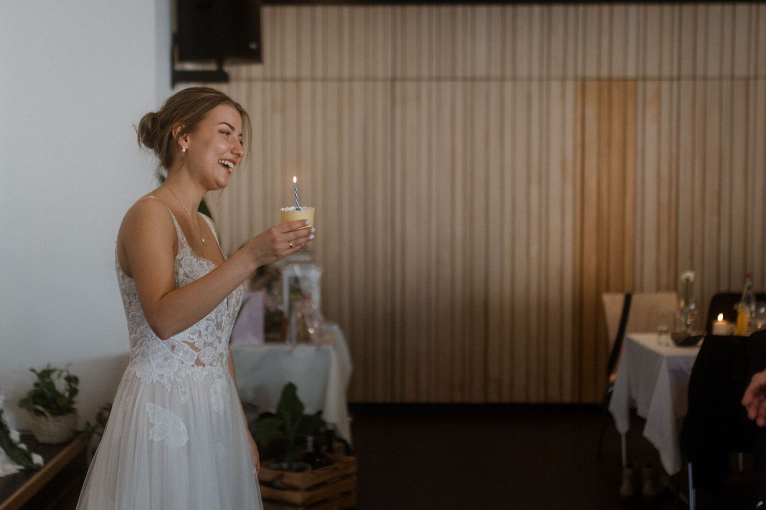 Bride laughing while holding sparkler during evening wedding celebration.